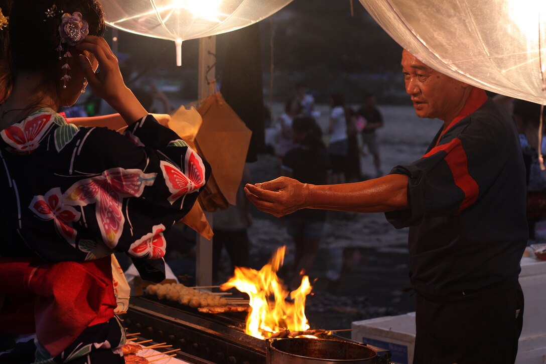 A vendor at the Nishiki River Water Festival takes an order for flame-grilled kabobs Saturday. A massive line of tents offered a variety of unique snacks, desserts and beverages for every taste.