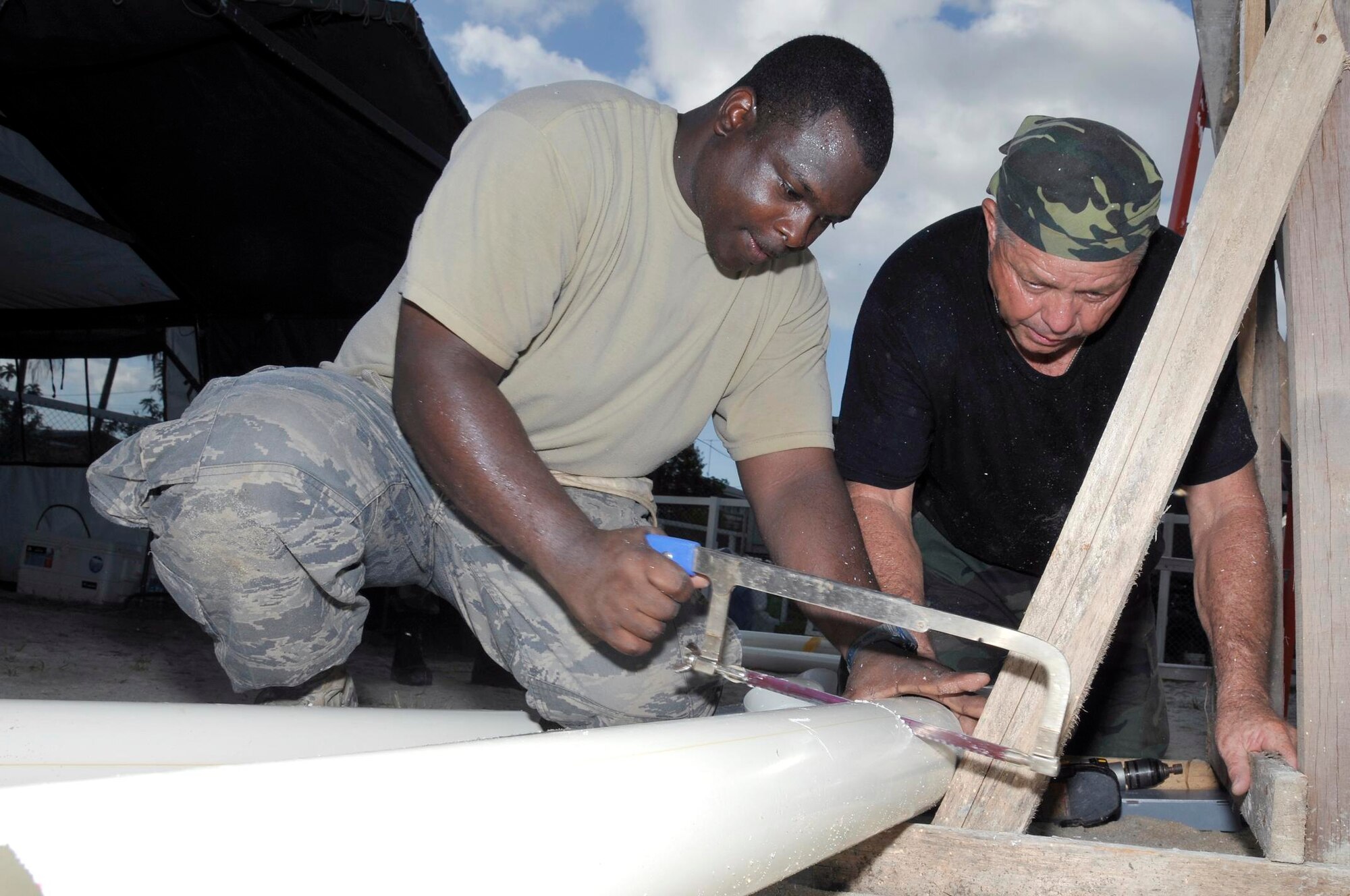 Tech Sgt. Ray Ball, heating, ventilating, and air conditioning craftsman, and Master Sgt. Victor Price, a engineering craftsman, both from the 301st Civil Engineer Squadron, Naval Air Station Joint Reserve Base Fort Worth, Texas, cut a piece of pipe for the new gutters at Timehri Nursery school July 29, 2009 in Georgetown, Guyana. Sergeant Ball, and Sergeant Rice are finishing up the renovation of the school. (U.S. Air Force photo by Airman 1st Class Perry Aston) (Released)