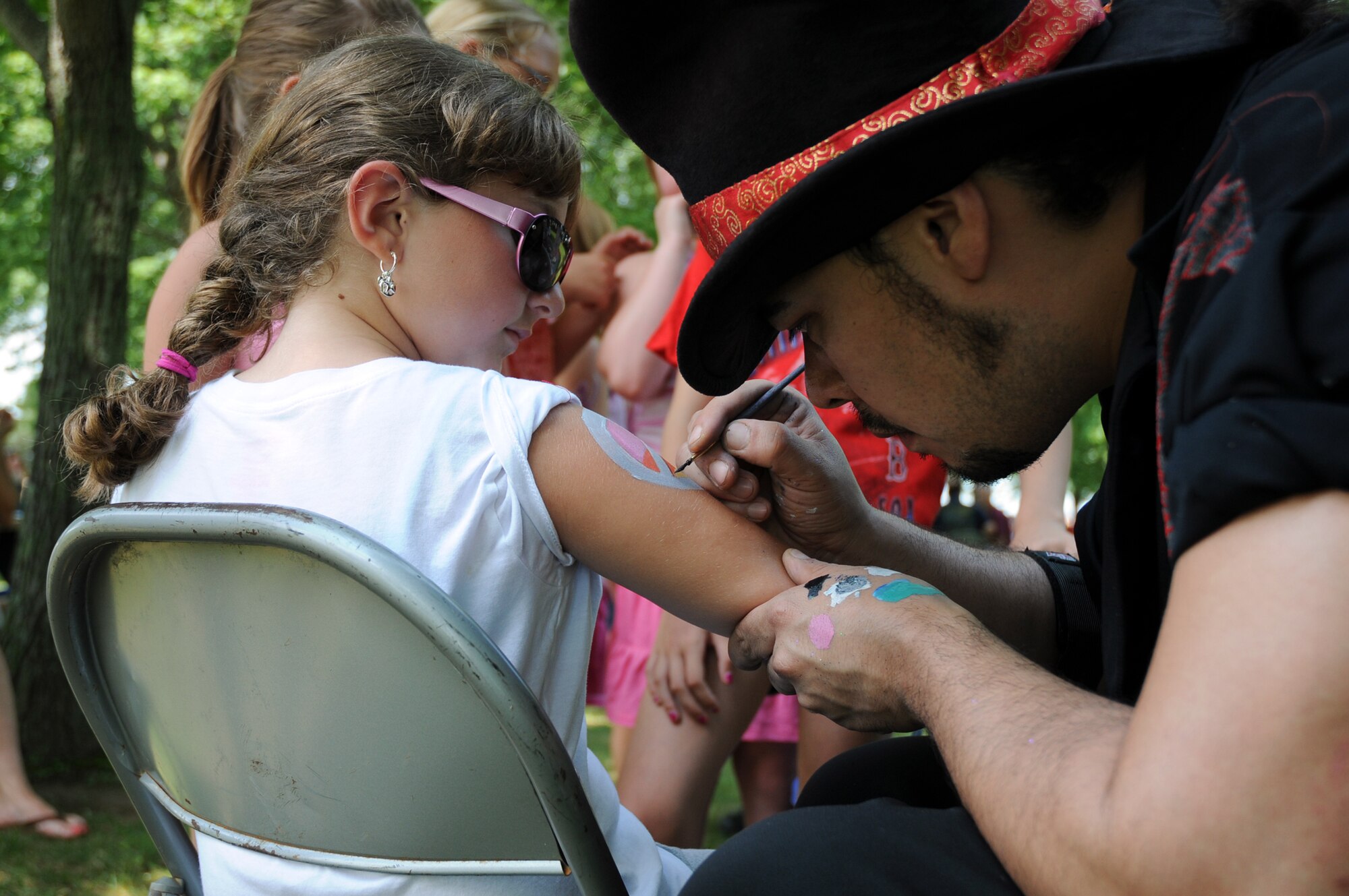 Face Painter Peter Domingo decorates the arm of Kali Kasprenski, 8, during the 512th Airlift Wing picnic Aug. 1 at the Eagle's Nest picnic area. Kali is the daughter of Senior Airman Scott Kasprenski of the 512th Maintenance Squadron. More than 1,100 reservists and their families attended the biannual event. (U.S. Air Force photo/Capt. Marnee A.C. Losurdo)