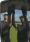 (Left) Tech. Sgt. James Hedtkamp, 556th Red Horse Squadron, and Senior Airman LeKeya Parks, 919th Services Flight, roll up the window flaps July 30 during the building of a tent for a deployment training exercise.   Services members built two tents to be used as a kitchen and dining facility as part of their training.  The building was plagued by frequent thunderstorms that popped up throughout the process.  Personnel prepared and ate a meal from the tents Aug. 1 during the UTA weekend.  (U.S. Air Force photo/Staff Sgt. Samuel King Jr.)