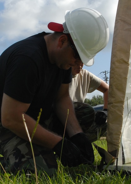 Tech. Sgt. James Hedtkamp, 556th Red Horse Squadron, secures the flaps tightly July 30 during the building of a tent for 919th Services Flight who participated in deployment training exercise.  Services members built two tents to be used as a kitchen and dining facility as part of their training.  The building was plagued by frequent thunderstorms that popped up throughout the process.  Personnel prepared and ate a meal from the tents Aug. 1 during the UTA weekend.  (U.S. Air Force photo/Staff Sgt. Samuel King Jr.)