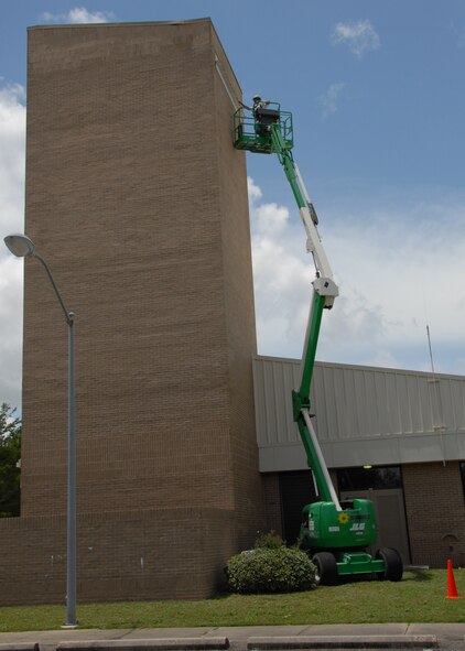 A raised lift stretches up the parachute shop allowing painters from Washington Painting to paint the top of the building.  (U.S. Air Force photo/Staff Sgt. Samuel King Jr.)