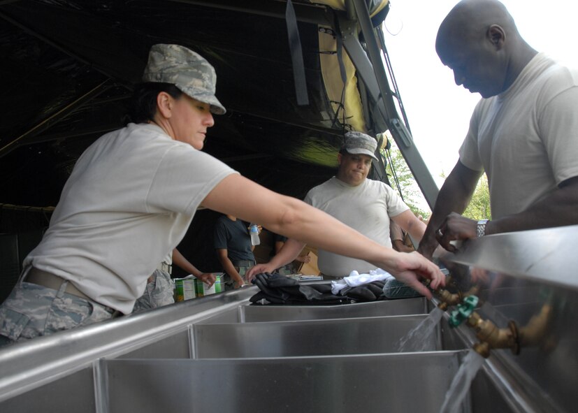 (Left) Staff Sgt. Lucinda Valdez and Master Sgt. Ike Kenty, 919th Services Flight, test the water lines in the kitchen tent Aug. 1 after building the tent for a deployment training exercise.   Services members built two tents to be used as a kitchen and dining facility as part of their training.  The building was plagued by frequent thunderstorms that popped up throughout the process.  Personnel prepared and ate a meal from the tents Aug. 1 during the UTA weekend.  (U.S. Air Force photo/Staff Sgt. Samuel King Jr.)