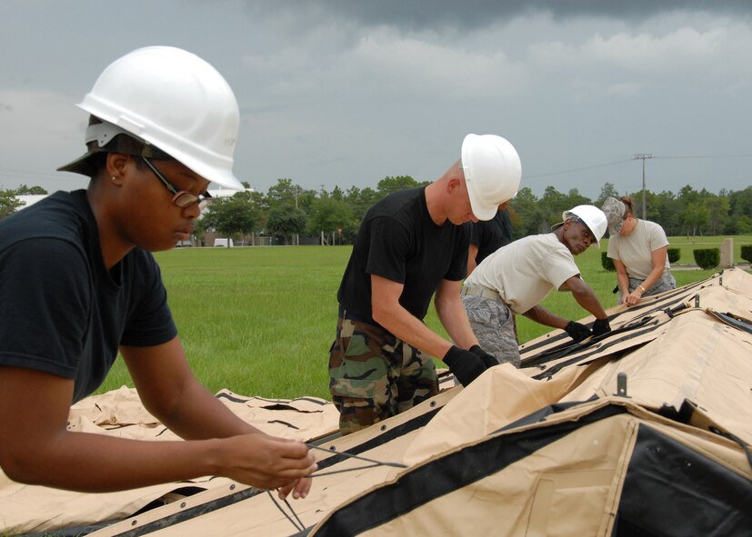 Senior Airman Deandrea Dorsey, 919th Services Flight, and others tie down the flaps July 31 while building a tent to be used as a kitchen for a deployment training exercise.   Services members built two tents to be used as a kitchen and dining facility as part of their training.  The building was plagued by frequent thunderstorms that popped up throughout the process.  Personnel prepared and ate a meal from the tents Aug. 1 during the UTA weekend.  (U.S. Air Force photo/Staff Sgt. Samuel King Jr.)