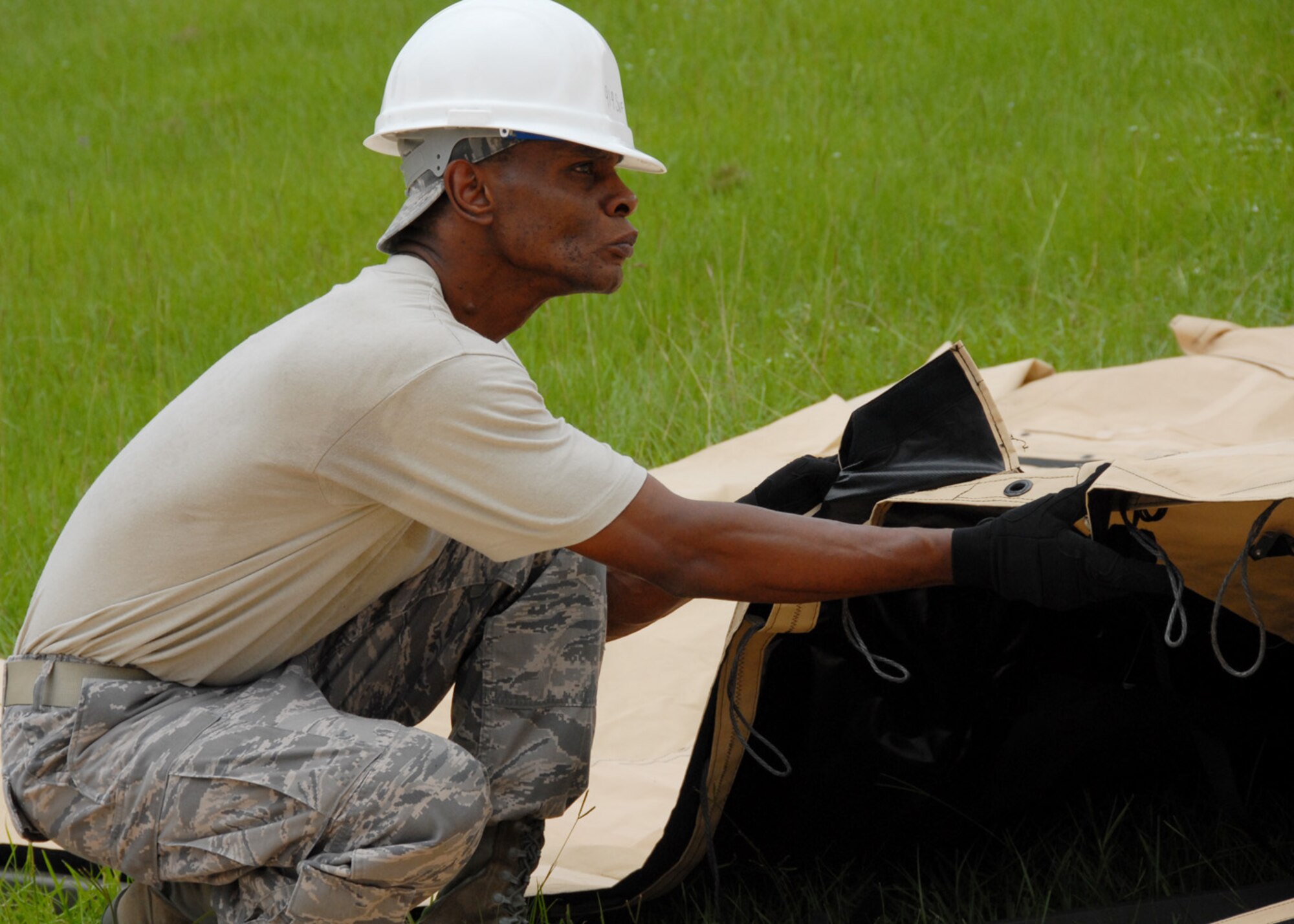 Tech Sgt. James Ivey, 919th Services Flight, pulls down one of the flaps July 31 while building a tent to be used as a kitchen for a deployment training exercise.   Services members built two tents to be used as a kitchen and dining facility as part of their training.   The building of the tents was plagued by frequent thunderstorms that popped up throughout the process.  Personnel prepared and ate a meal from the tents Aug. 1 during the UTA weekend.  (U.S. Air Force photo/Staff Sgt. Samuel King Jr.)