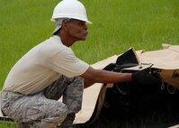 Tech Sgt. James Ivey, 919th Services Flight, pulls down one of the flaps July 31 while building a tent to be used as a kitchen for a deployment training exercise.   Services members built two tents to be used as a kitchen and dining facility as part of their training.   The building of the tents was plagued by frequent thunderstorms that popped up throughout the process.  Personnel prepared and ate a meal from the tents Aug. 1 during the UTA weekend.  (U.S. Air Force photo/Staff Sgt. Samuel King Jr.)