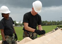 (Right) Tech. Sgt. Wesley Barnett, 919th Services, explains how to secure the ties on the tent flaps to Staff Sgt. Sharon Edwards, 919th Services, July 31 while building a tent to be used as a kitchen for a deployment training exercise.   Services members built two tents to be used as a kitchen and dining facility as part of their training.   The building of the tents was plagued by frequent thunderstorms that popped up throughout the process.  Personnel prepared a meal for the 919th Security Forces Squadron from the tents Aug. 1 during the UTA weekend.   (U.S. Air Force photo/Staff Sgt. Samuel King Jr.)