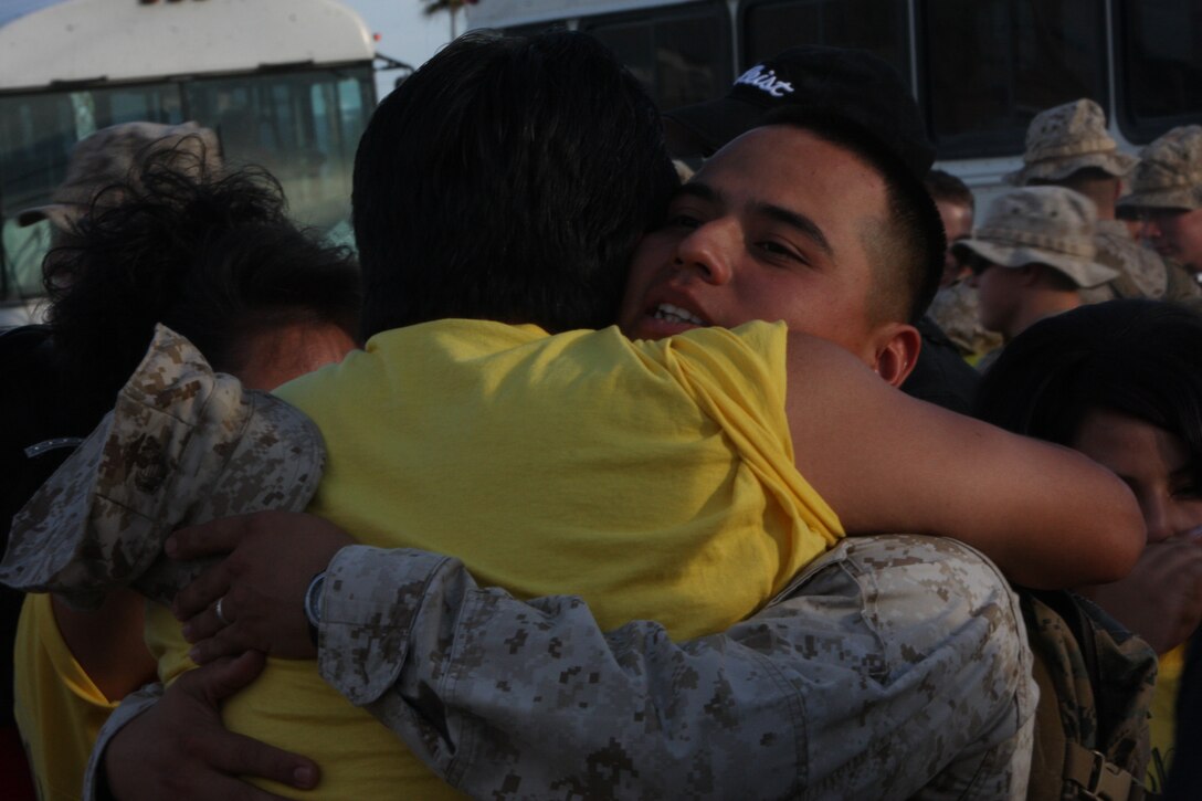 Cpl. Marcus Chischilly, a team leader with Baker Company, 1st Battalion, 7th Marine Regiment and native of Phoenix, Ariz., embraces family members during the 1/7 advanced party homecoming at Victory Field Aug. 3. Chischilly’s family designed T-shirts to show their support and excitement for his return.