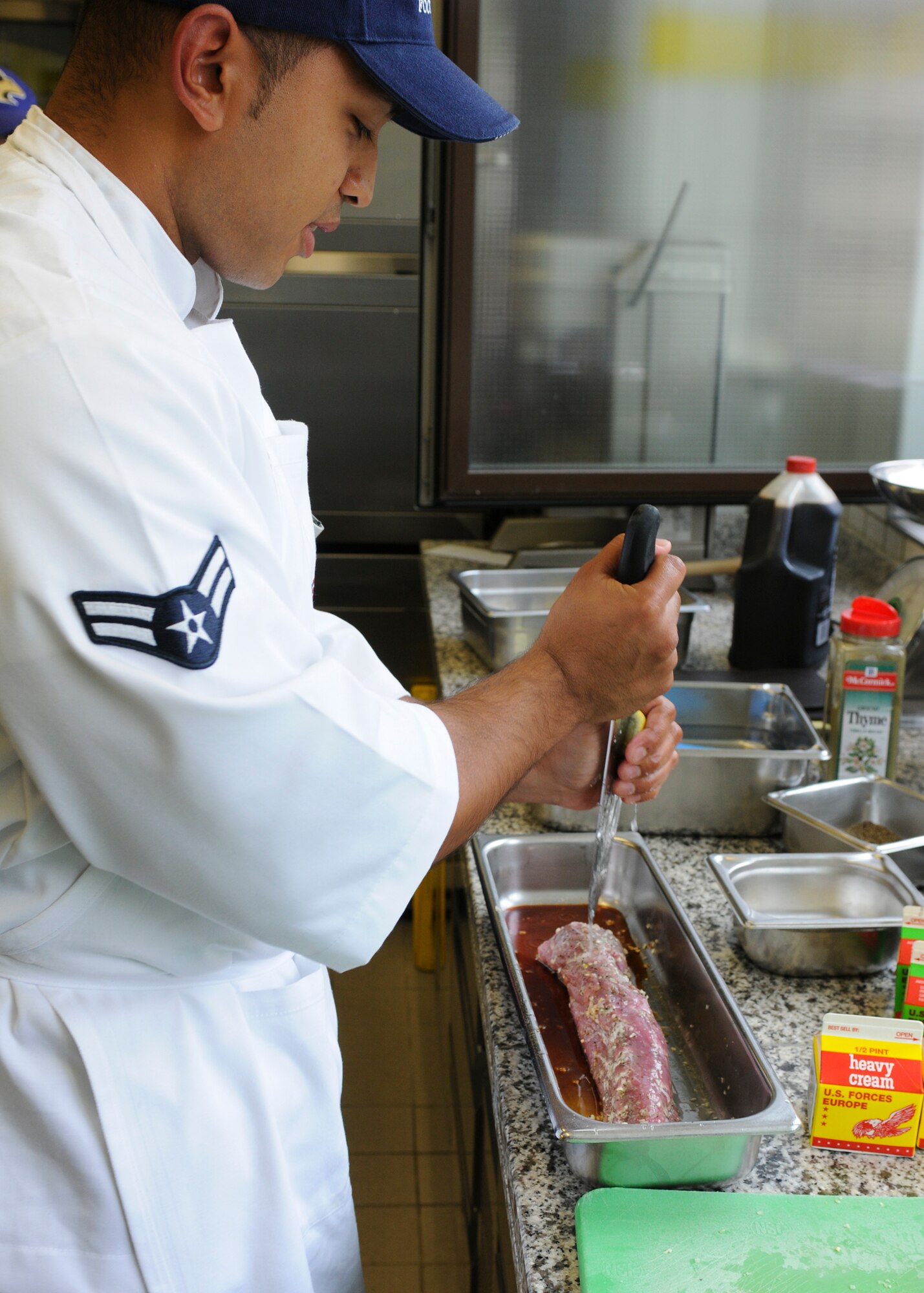 SPANGDAHLEM AIR BASE, Germany -- Airman 1st Class Jason Sugimoto, 52nd Force Support Squadron food service journeyman, squeezes lemon over a piece of pork before baking it July 30 at Kapaun Air Station, Germany. He was named one of two top chefs at the competition. Airman Sugimoto placed runner-up for the competition and was selected to attend the Culinary Institute of America in Napa Valley, California for training along with Iron Chef winner Staff Sgt. Kiana Mobley, 48th Force Support Squadron, Royal Air Force Lakenheath. (U.S. Air Force photo by Airman 1st Class Nathanael Callon)