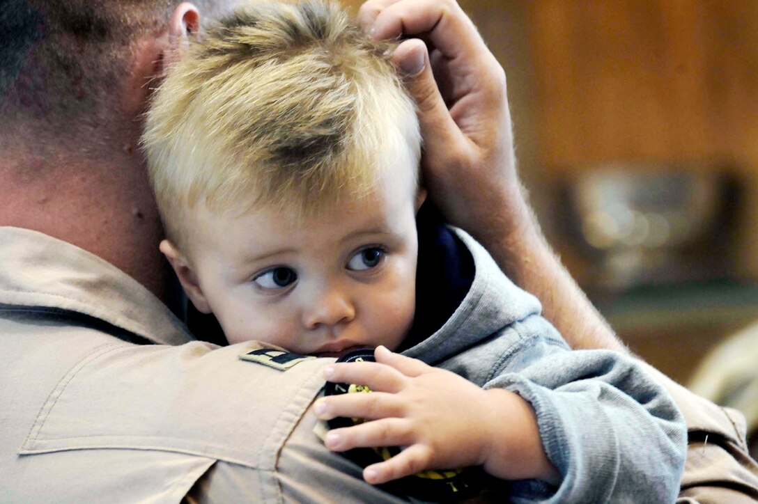 A weapons systems officer assigned to the 37th Bomb Squadron holds his son before deploying from Ellsworth Air Force Base, S.D. recently. Airmen representing various specialties deployed in support of operations in Southwest Asia. (U.S. Air Force photo/Airman 1st Class Corey Hook)