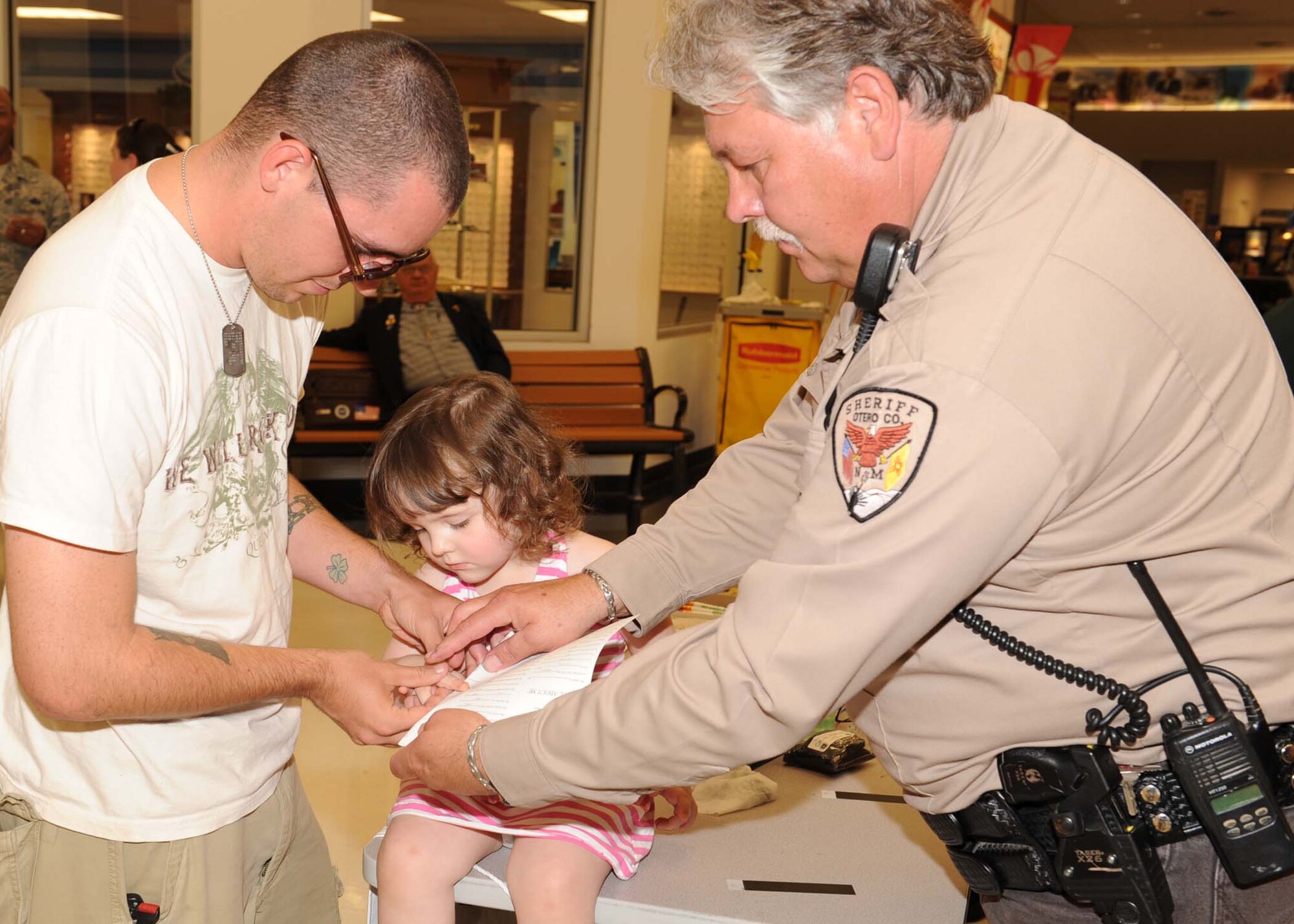 HOLLOMAN AIR FORCE BASE, N.M. -- Haley Crosby, daughter of Jeremiah Crosby, gets fingerprinted by Deputy Sheriff Frank Mackewich, Otero County Sheriff's Department, July 31, at the Base Exchange here. The whole process took approximately two minutes and can add to children's security by providing a positive ID. (U.S. Air Force photo by Senior Airman Rachel Kocin)