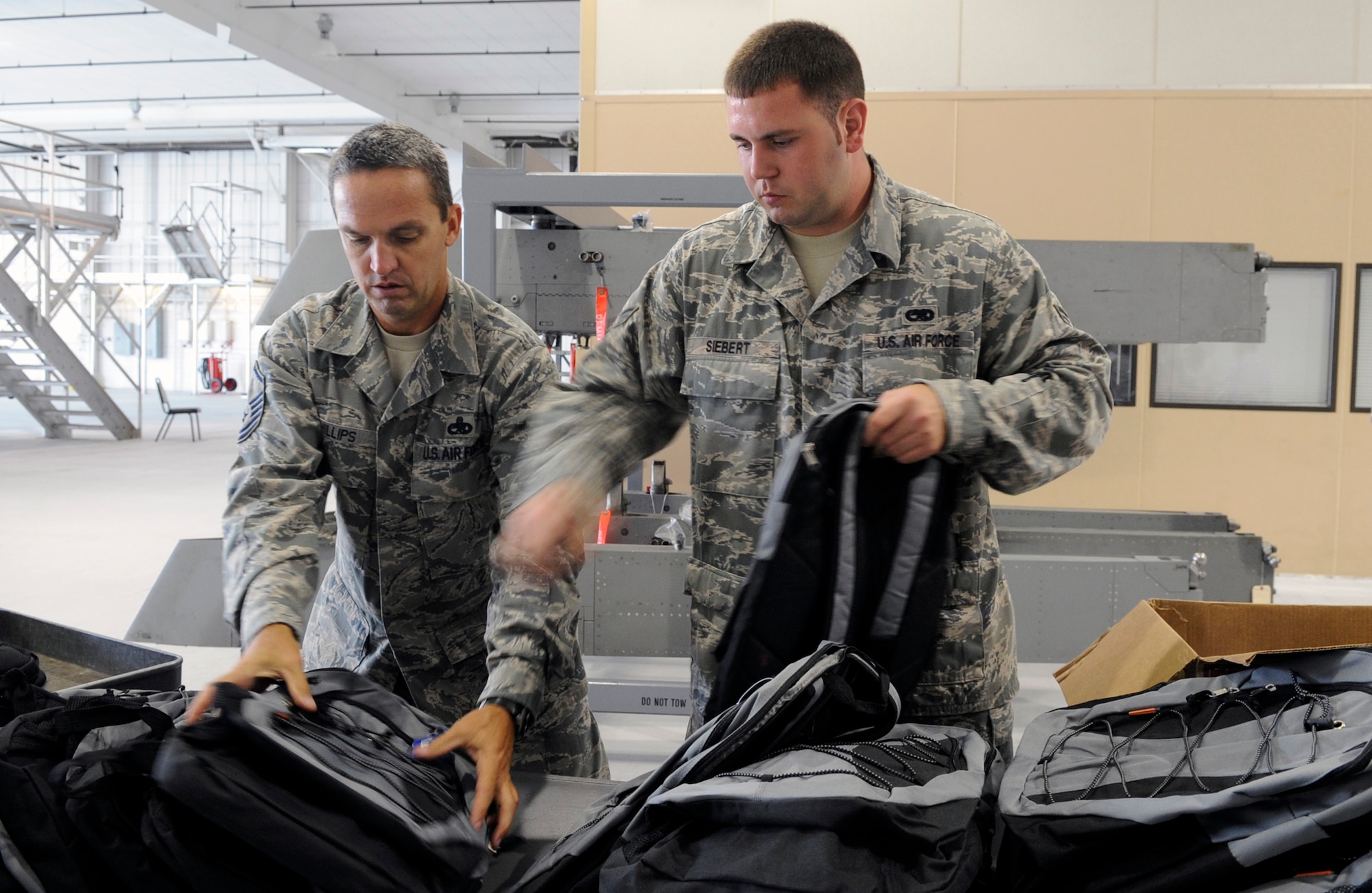 LANGLEY AIR FORCE BASE, Va.-- Master Sgt. David Phillips, 1st Equipment Maintenance Squadron conventional maintenance non-commissioned officer-in-charge,  and Senior Airman Michael Siebert, 1st EMS munitions inspection crew member, organize backpacks with school supplies during the Backpack Brigade 2009 here Aug. 3. Airmen from different squadrons volunteered to help fill up backpacks with school supplies, donated by the Langley’s Officers' Spouses Club and the local community. (U.S. Air Force Photo/Senior Airman Dana Hill)