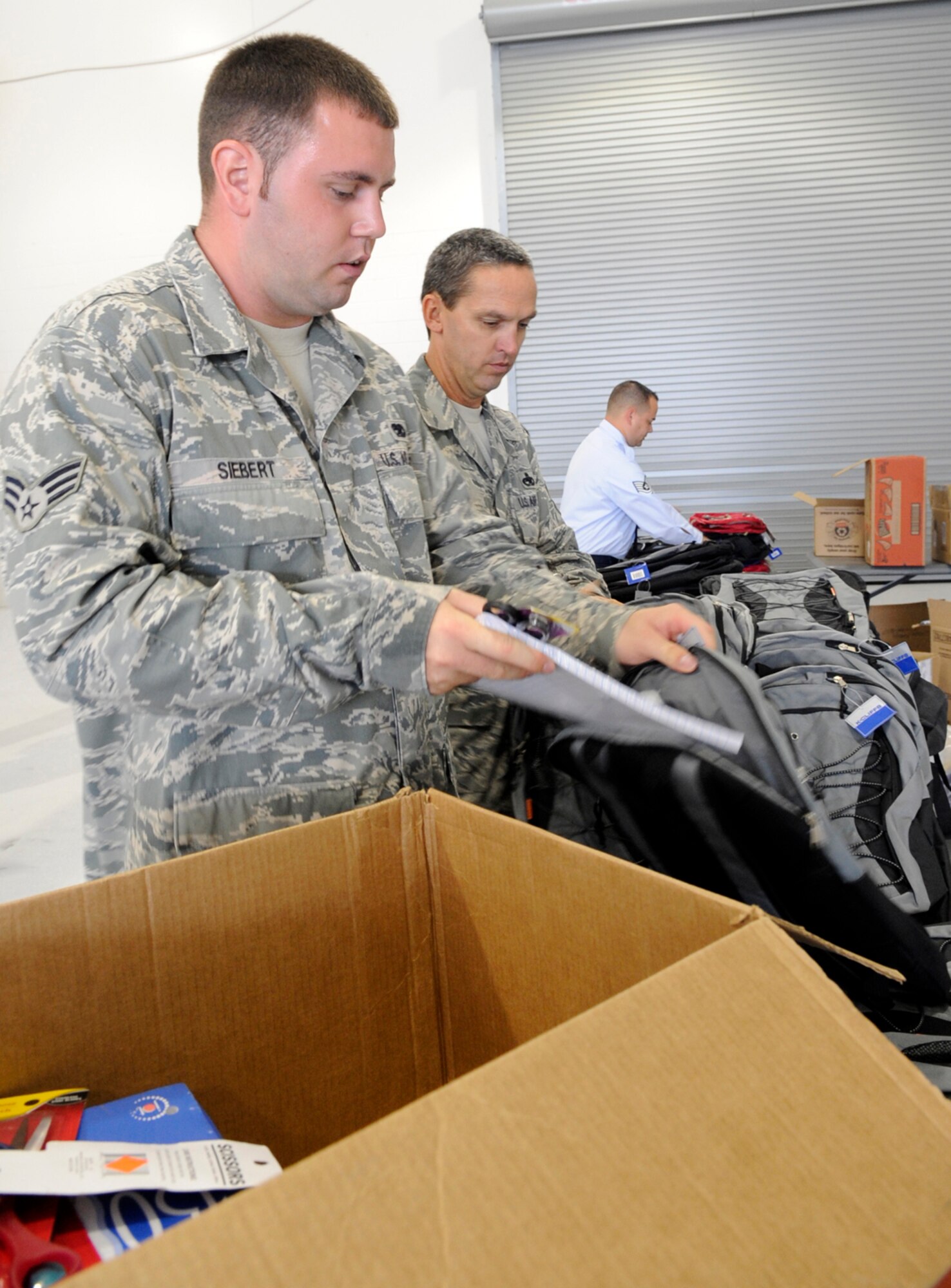 LANGLEY AIR FORCE BASE, Va.-- Master Sgt. David Phillips, 1st Equipment Maintenance Squadron conventional maintenance non-commissioned officer-in-charge, and Senior Airman Michael Siebert, 1st EMS munitions inspection crew member, fill backpacks with school supplies during the Backpack Brigade 2009 here Aug. 3. Airmen from different squadrons volunteered to help fill up backpacks with school supplies, donated by the Langley’s Officers' Spouses Club and the local community. (U.S. Air Force Photo/Senior Airman Dana Hill)