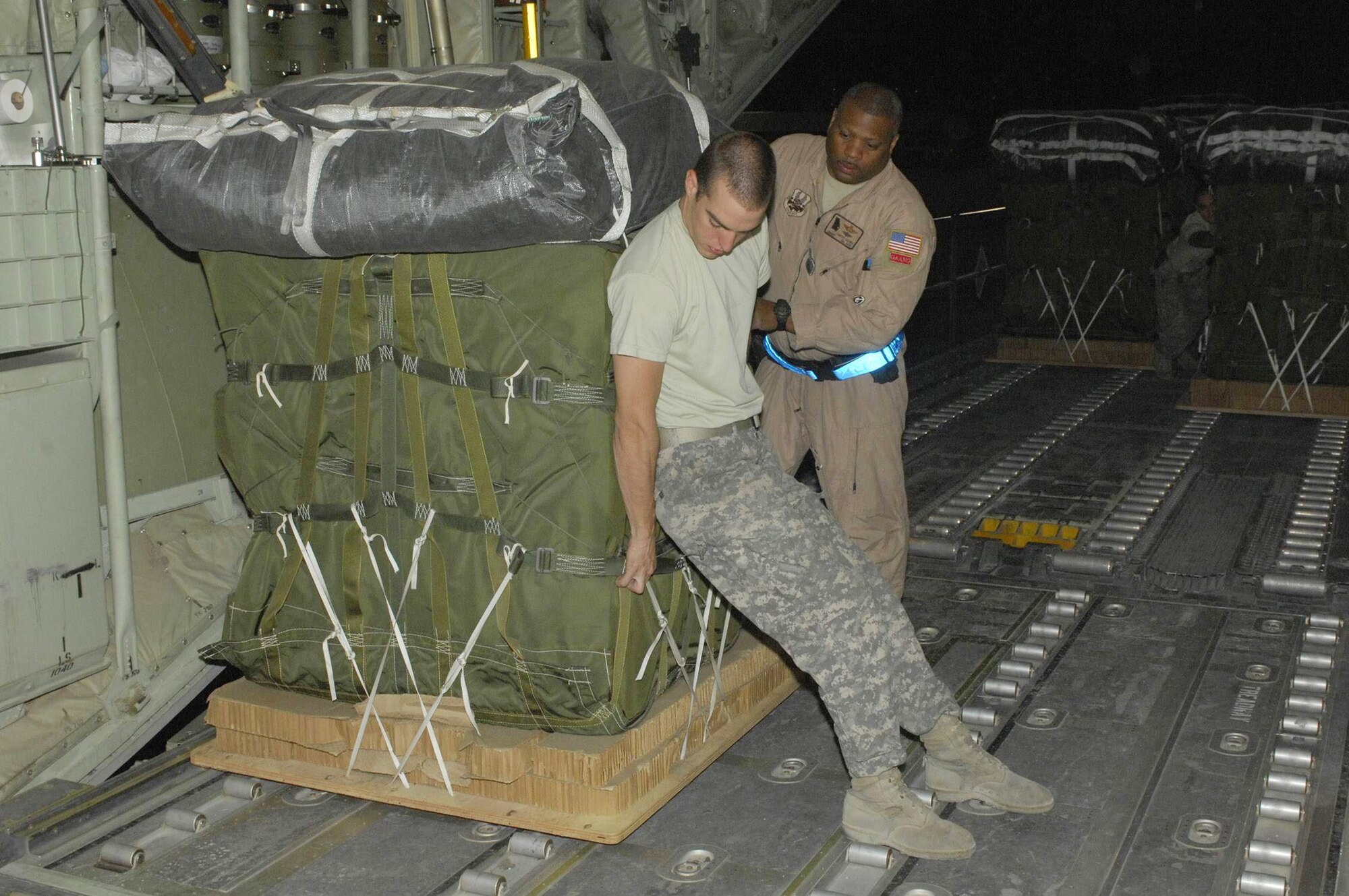 Army Specialist Joshua Vazquez helps Senior Master Sgt. Timothy Gaines move a pallet onto a C-130 Hercules cargo bay. The duo were loading the Hercules for an airdrop mission. Specialist Vazquez is deployed from Fort Bragg, N.C., and hails from El Centro, Calif. Sergeant Gaines' is with the 165th Airlift Wing, a Georgia Air National Guard unit deployed from Savannah, Ga., which is also his homeown. Specialist Vazquez is with the 612th Port Master Detachment in Southwest Asia. (U.S. Air Force photo/Tech. Sgt. John Jung)