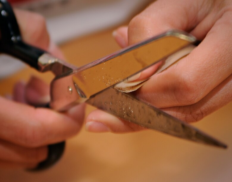 SPANGDAHELM AIR BASE, Germany - Jessica Silvia, wife of Master Sgt. Art Silvia, 52nd Civil Engineer Squadron, cuts a piece of velcro to fit a pair of modified boxers while volunteering for "Sew Much Comfort" July 31. Twenty-five volunteers worked from 9:30 a.m. to 2:30 p.m. to assemble 60 pairs of boxers while 22 pairs were completed. Since the program started in October 2008 more than 150 pairs of boxers have been completed to send to Landstuhl Regional Medical Center's chaplain's closet, where they will be available to wounded warriors.  (U.S. Air Force photo by Senior Airman Benjamin Wilson)