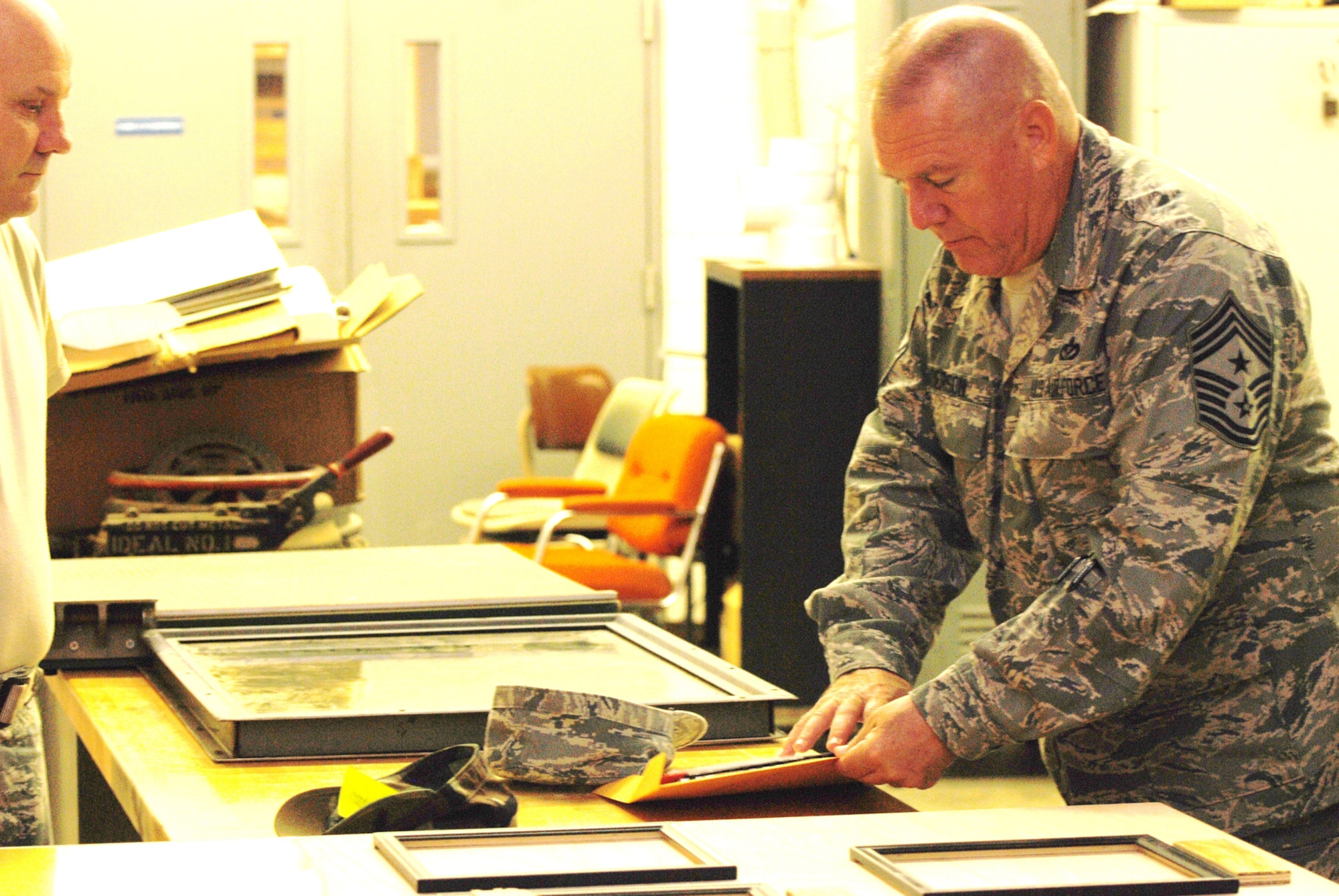 Chief Master Sgt. John Anderson, 94th Airlift Wing Command Chief, is briefed by Staff Sgt. Charles Johnson, 94th Civil Engineer Squadron, on progress of an awards board for display at the 94th Airlift Wing headquarter building July 31. The display will feature photos of quarterly and annual award winners. (U.S. Air Force Photo/Senior Airman Quadoah Ford)