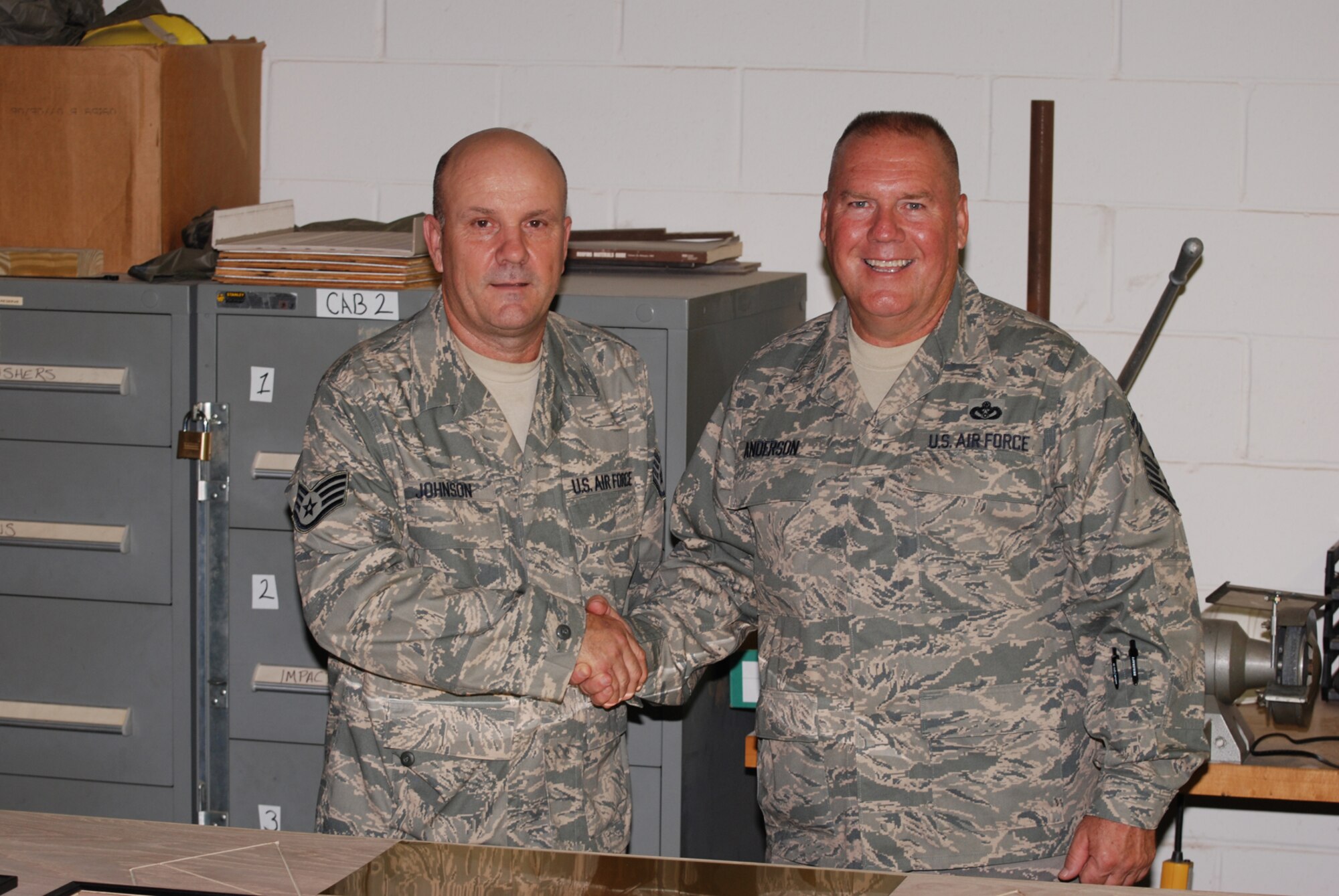 Chief Master Sgt. John Anderson, 94th Airlift Wing Command Chief, congratulates Staff Sgt. Charles Johnson, 94th Airlift Wing Civil Engineer Squadron, for a job well done on the progress of an awards board for the 94th Airlift Wing July 31. The display will feature photos of annual and quarterly award winners. (U.S. Air Force Photo/Senior Airman Quadoah Ford)