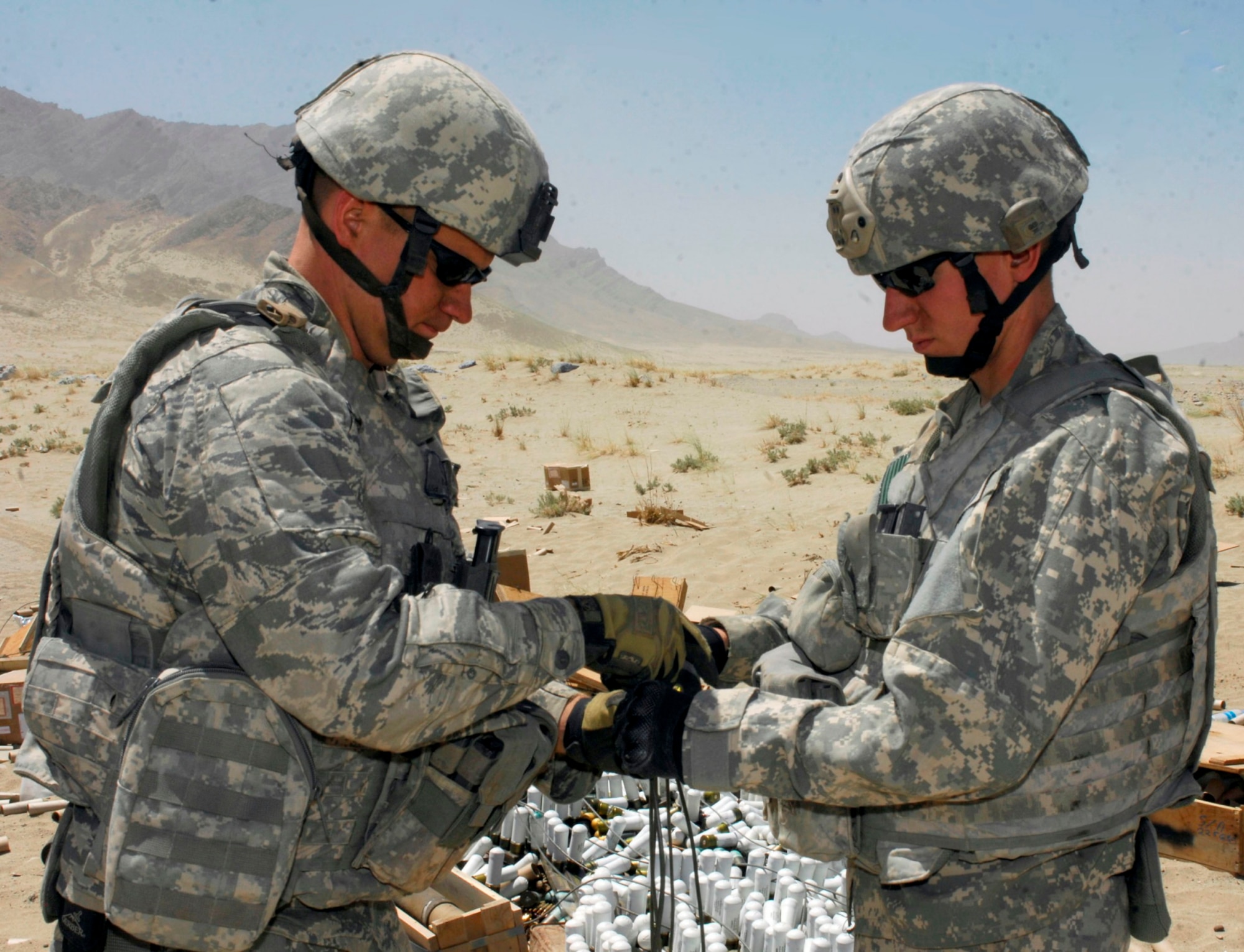 BAGRAM AIRFIELD, Afghanistan - Staff Sgts. Trent Rydberg (left) Greg Talley (right), 755th Air Expeditionary Group, Explosive Ordnance Disposal technicians tape together wire leads that are used to send firing signals to C-4 explosive charges attached to a cache of ordnance at a disposal range near BAF. Several hundred pounds of mixed ordinance, including discarded Soviet munitions from the 1970s, were disposed of Aug 2. Sergeant Rydberg is a reservist deployed from Scott Air Force Base, Ill. Sergeant Talley is deployed from Dyess AFB, Texas and hails from Rogers, Ark. (U.S. Air Force photo/Tech. Sgt. John Jung)