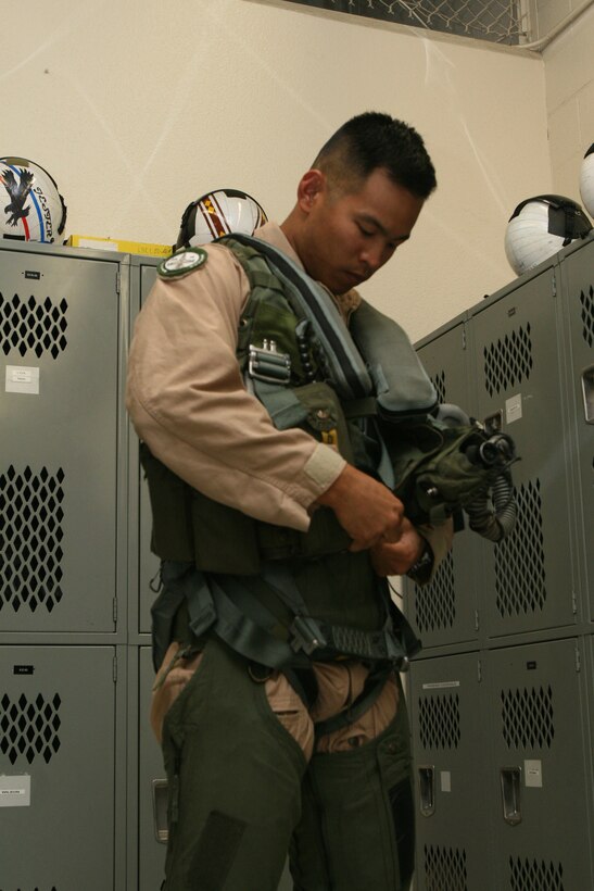 Capt. John Dinh, a pilot with Marine Fighter Attack Training Squadron 101, puts his gear on as he gets ready to go on a flight. The main components of the gear are the anti-g suit, the parachute harness, the helmet and the survival vest. The preparation that goes into every flight is several hours long.