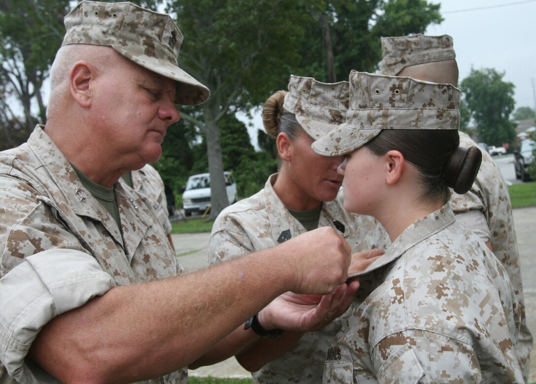 Maj. Gen. Paul E. Lefebvre, deputy commanding general, II Marine Expeditionary Force, promotes Corporals Amanda Miller, a generator mechanic with Combat Logistics Battalion 2, 2nd Marine Logistics Group, and her husband, Larry B. Miller, an electrician with Headquarters Battalion, 2nd Marine Division, to sergeant, Aug. 3, 2009, aboard Camp Lejeune, N.C.  The two credit each other with their career successes.::n::::n::