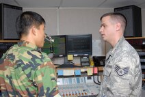 KUNSAN AIR BASE, Republic of Korea -- Staff Sgt. Michael Schocker, a broadcaster for Armed Forces Network, explains the radio system to a Korean high school student during a tour of the base here July 31.Throughout the visit, the students met with Airmen in different career fields to learn how each Airman contributes to the mission. The Airmen met with the students to learn about how they can be good neighbors and about the local culture. (U.S. Air Force photo/Staff Sgt. Darnell T. Cannady)