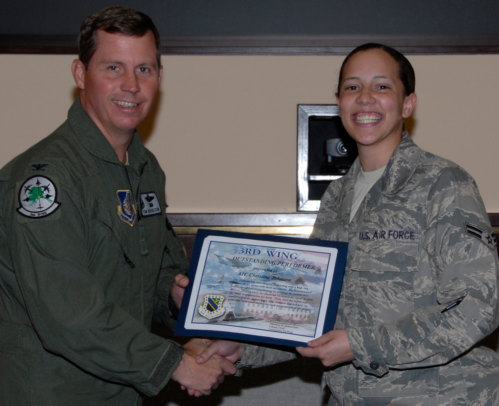 Airman 1st Class Christina Johnson, receives a 3rd Wing outstanding performer certificate from Col. Thomas Bergeson, 3rd Wing commander July 28. (U.S. Air Force photo/Senior Airman Cynthia Spalding)