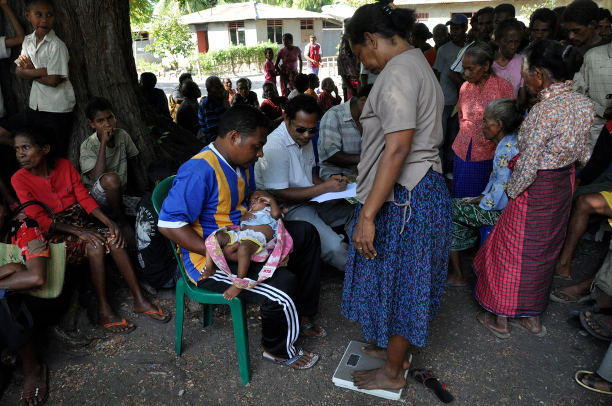 BIKELI, ATAURO – An East Timorese man holds a woman's baby so that she can be weighed in the registration area prior to being seen by U.S. Air Force and Royal Australian Regiment medical personnel. The team provided basic medical care by checking vital signs, checking for Malaria, conducting health assessments and distributing antibiotics and Tylenol during a humanitarian visit to the fishing village Bikeli, Atauro in support of  Pacific Angel 09 on July 21, 2009. Pacific Angel is a 13th Air Force led humanitarian assistance operation aimed at improving military civic cooperation between the United States and Timor Leste.  (U.S.  Air Force photo/Tech Sgt. Cohen A. Young)