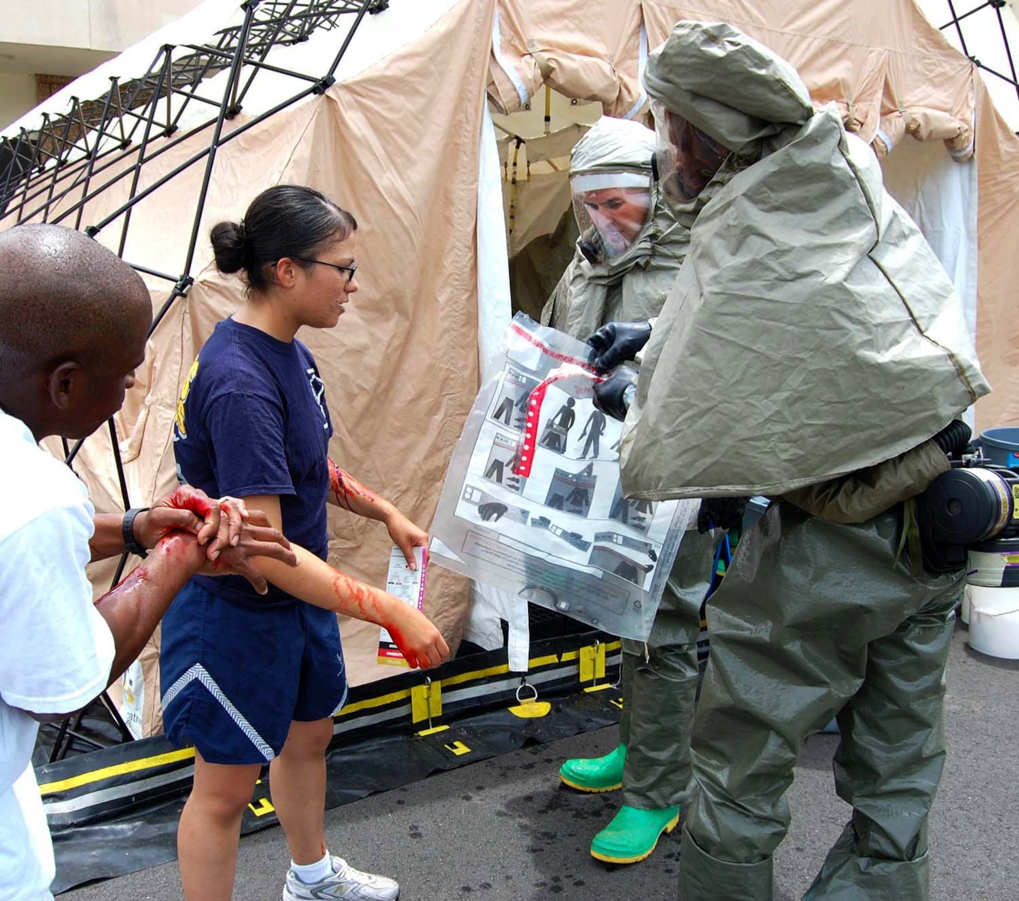 Airman 1st Class Eric Whitlow, left, and Airman Basic Christina Ortiz, 334th Training Squadron students, portray victims who hand over their personal belongings to Senior Airman Oruaron Idudhe, 81st  Surgical Oper-ations Squadron, and Staff Sgt. James Bowden, 81st Medical Operations Squadron, at the start of the decontamination process July 29 during the all hazard response training field exercise.  AHRT is an Air Force chief of staff education, training and exercise program that allows the installation commander to evaluate emergency response capabilities.  (U.S. Air Force photo by Steve Pivnick)