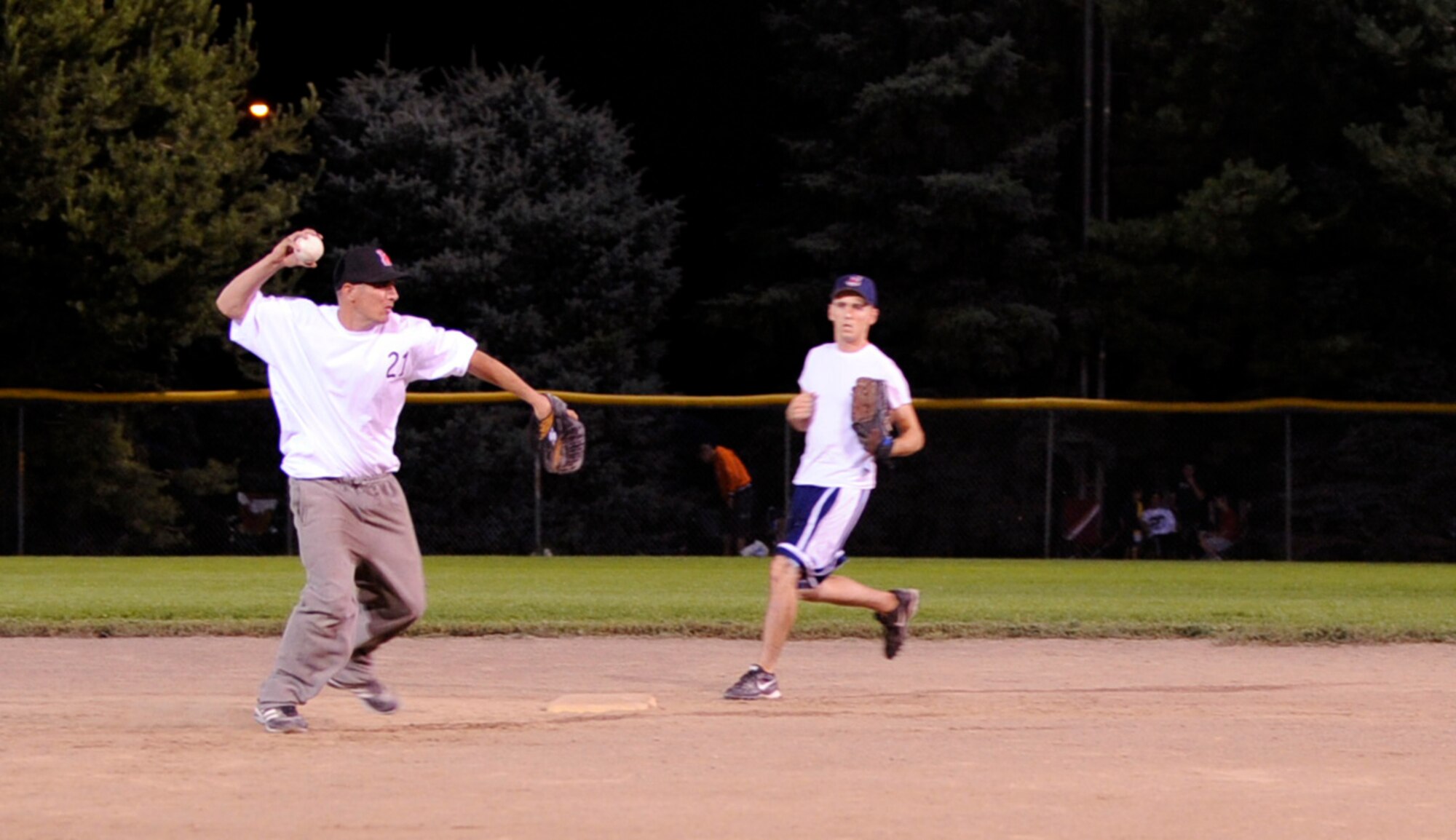 MOUNTAIN HOME AIR FORCE BASE, Idaho -- John Roth, 366th Component Maintenance Squadron shortstop, makes a throw to first as Timoth Weahry covers second base during an Operation Warmheart softball game July 31. AMXS annihilated CMS 19-3. The softball tournament, won by Thrifty's Shake ‘n Bake for the third year in a row, kicked off at 3 p.m. July 31 and ran through Aug. 2 with games played 24 hours a day. Operation Warmheart -- run by the first sergeants council and other committee members -- raises funds to help military families when times get tough financially. (U.S. Air Force photo by Airman 1st Class Debbie Lockhart)
