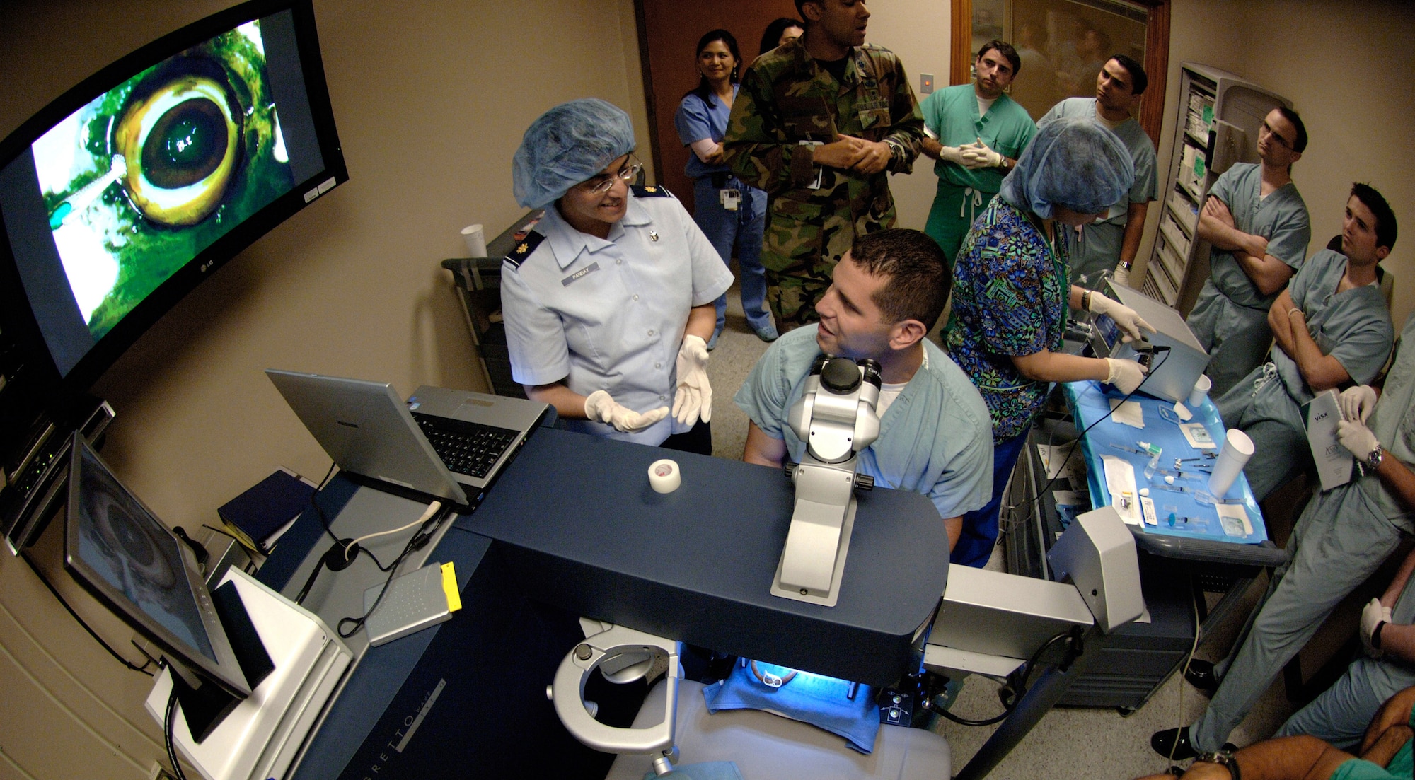 Ophthalmologist Maj. (Dr.) Vasudha Panday (front left) discusses using the a microkeratome, a precision cutting tool used in LASIK surgery, with Capt. (Dr.) Michael Parsons (center) at the Joint Refractive Surgery Center, Lackland Air Force Base, Texas. Both Dr. Panday and Dr. Parsons are members of the 59th Surgical Specialties Squadron. Refractive surgery technician Rita Garza (right), 59th SSS, prepares the microkertome for Dr. Parsons to practice cutting on a training eyeball. Lt. Col. (Dr.) Sanford Roberts (back left), 59th SSS, discusses the procedure with ophthalmology residents from Wilford Hall Medical Center; Brooke Army Medical Center, Ft. Sam Houston, Texas; and University of Texas Health Science Center, San Antonio.  (U.S. Air Force photo/Master Sgt. Kimberly A. Yearyean-Siers)