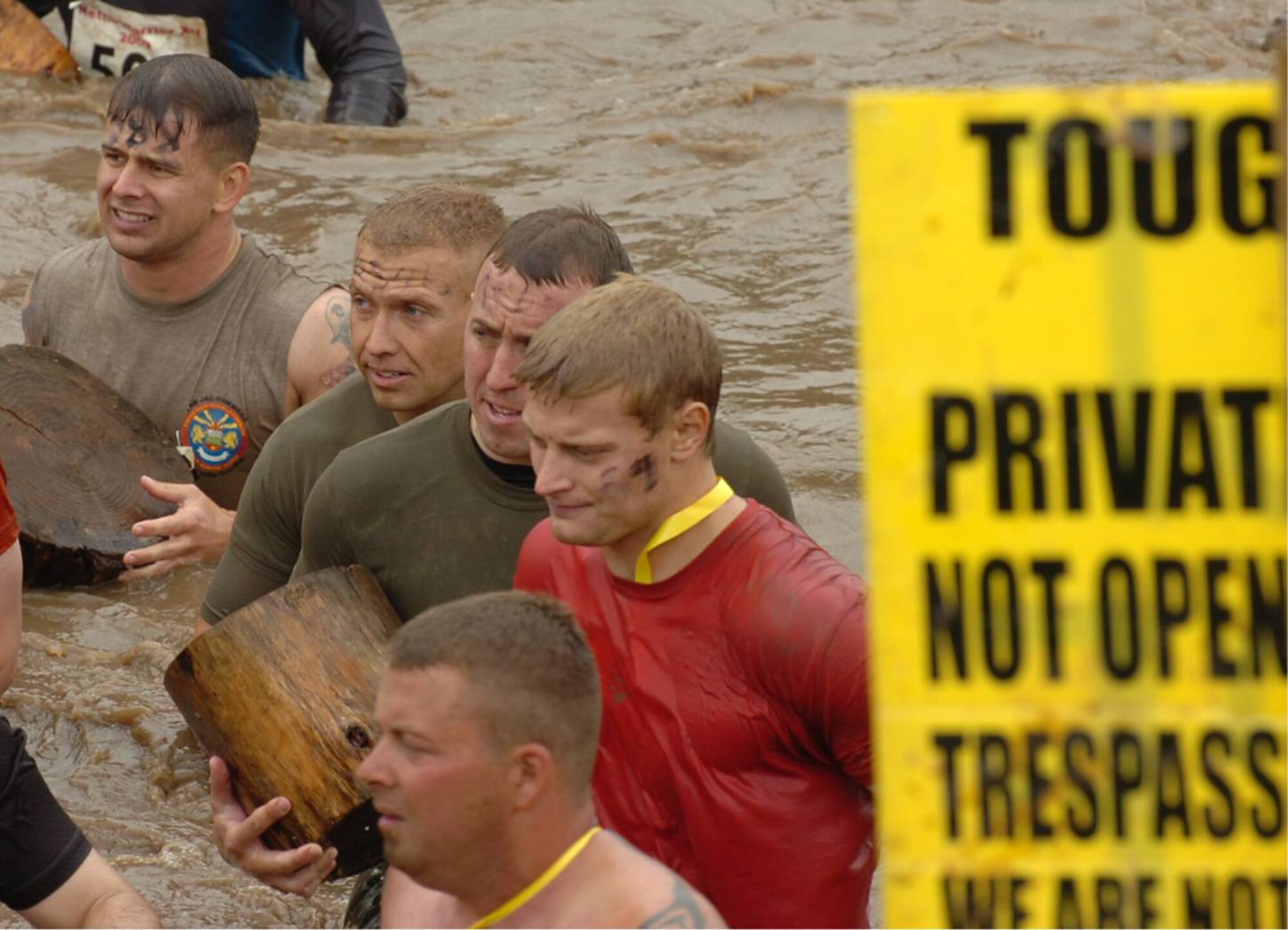 Carrying a log across a cold, muddy stream, Marine Corps Sergeants Matthew Johnson, Stacy F. Jacobs, and Daniel K. Butrim (in brown shirts) compete in the UK TOUGH GUY summer 2009 competition in Old Perton, England.  The Marines are assigned to RAF Molesworth UK (U.S. Air Force Photo by Staff Sgt. Rachel A. Goff)