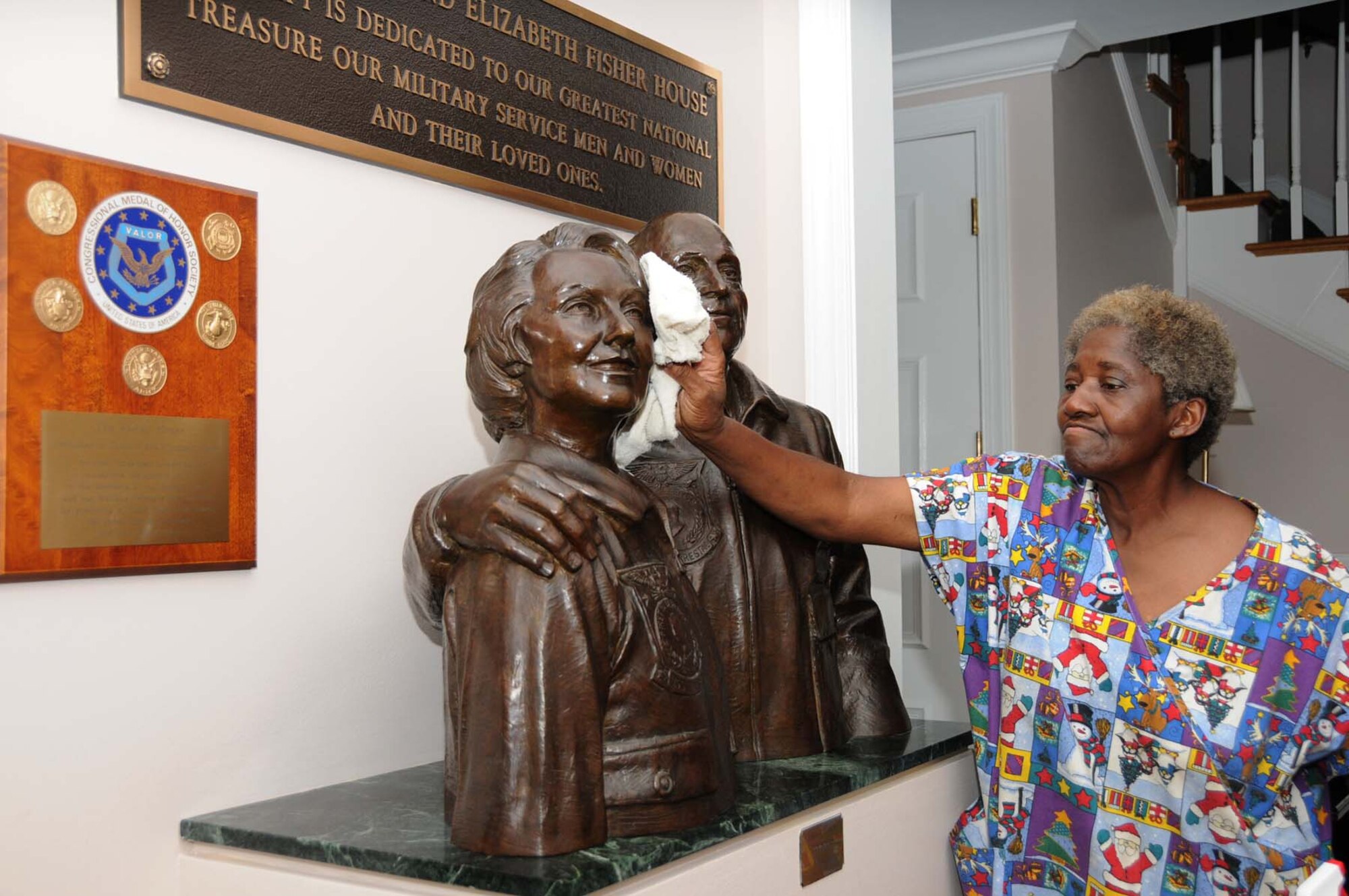 Longtime housekeeper Mary Burley dusts the statue of Zachary and Elizabeth Fisher in the foyer.   (U.S. Air Force photo by Kemberly Groue)