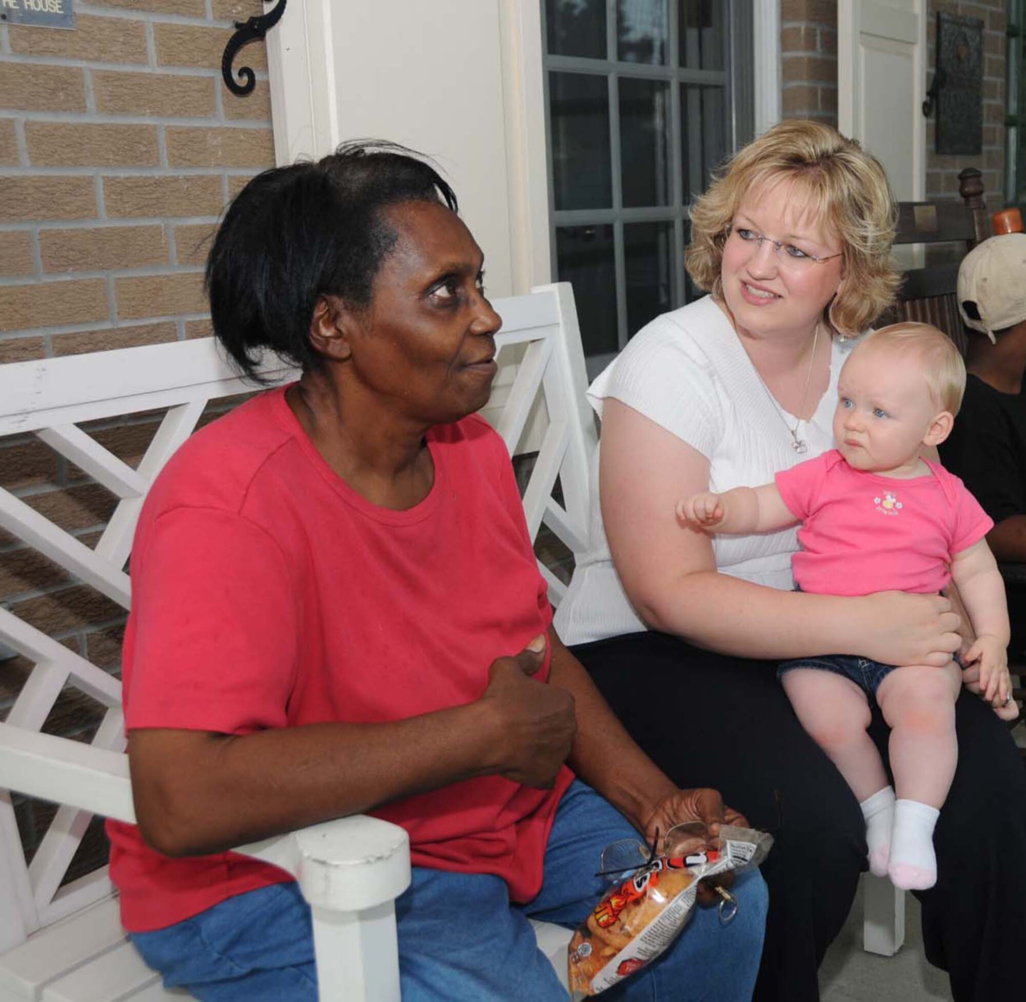 Fisher House guest Ruby Richardson, who’s having a procedure done at the VA, chats on the front porch with Christina Jones and her 9-month-old daughter, Hanna, while Lieutenant Jones and his classmates fix dinner.  (U.S. Air Force photo by Kemberly Groue)