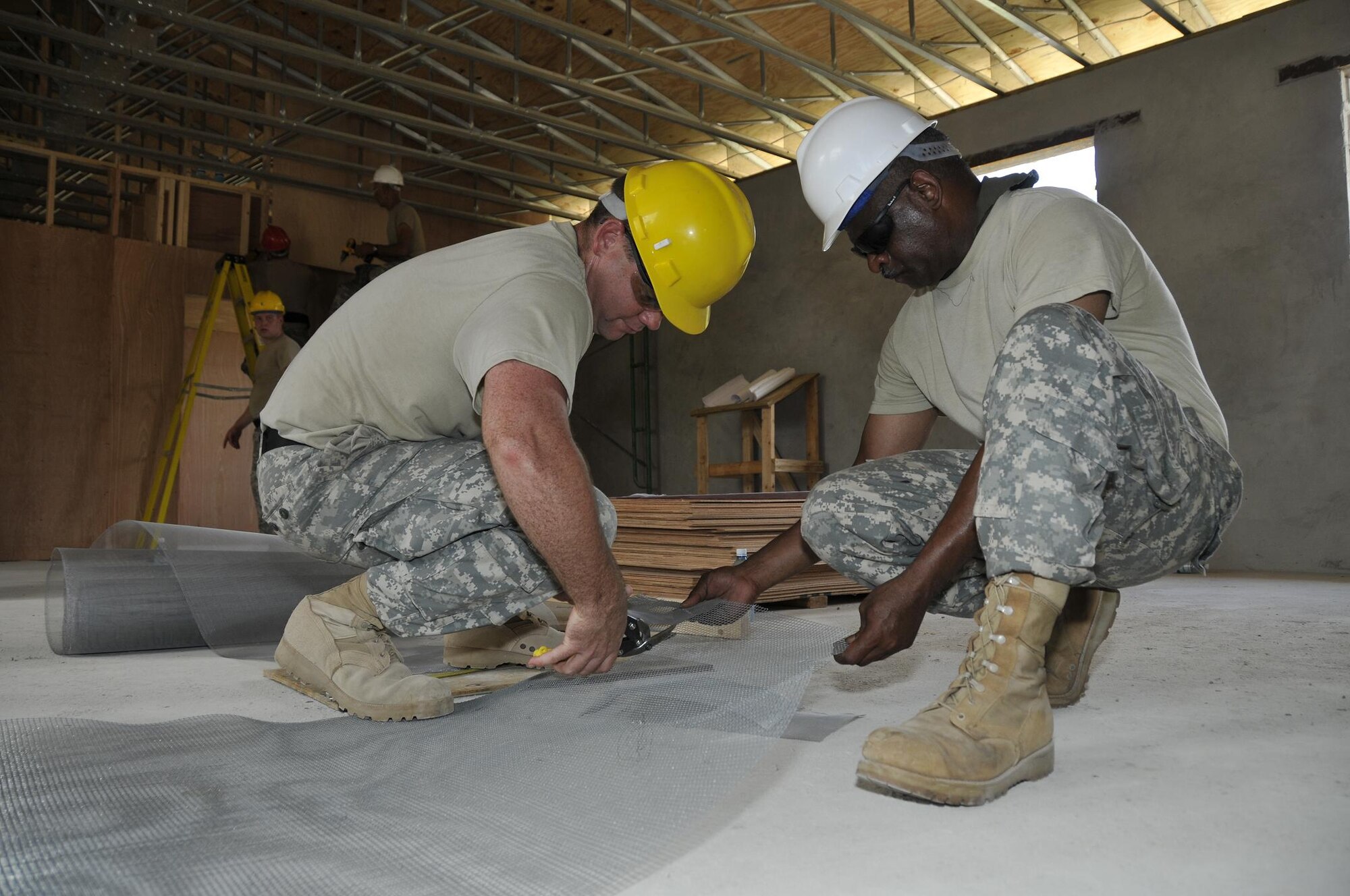 Sgt. 1st Class Clifford Gardner, Chemical Warfare specialist from the 878th Engineer Battalion, Georgia Army National Guard, holds a metal screen while Sgt. 1st Class Charles Wilkinson, signal systems support specialists, cuts it, July 3, 2009 in Georgetown, Guyana. The screen will prevent bugs and animals from entering the roof vents. (U.S. Air Force photo by Airman 1st Class Perry Aston) (Released)