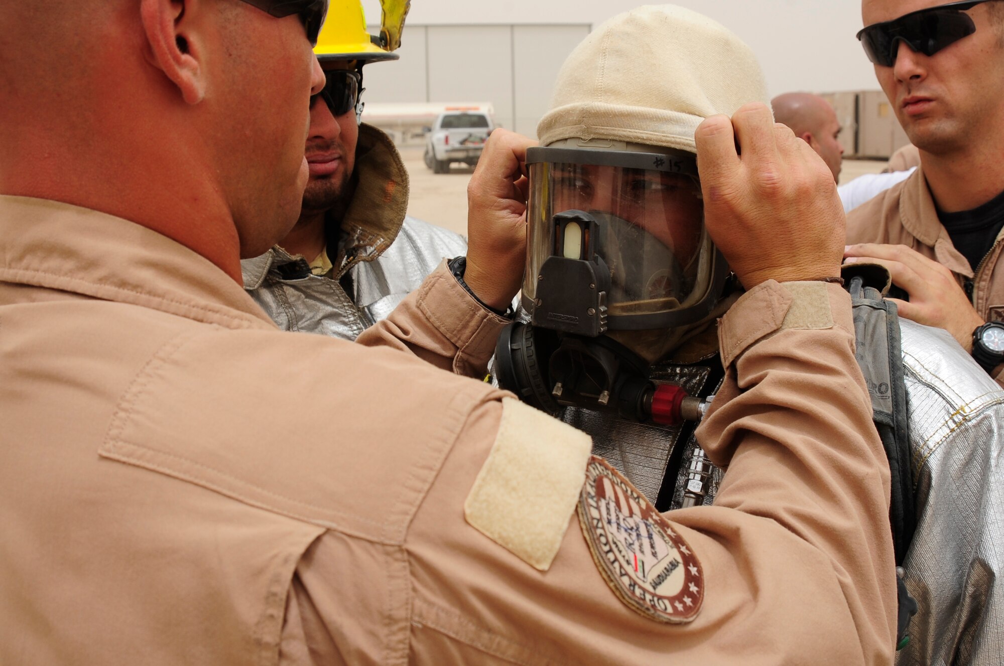 ALI BASE, Iraq - Senior Airman John Black from the 407th Expeditionary Civil Engineer Squadron assists an Iraqi firefighter from the Dhi Qar Province, An Nasariyah city,  in positioning his safety equipment and mask before a training event here August 3.  Airmen from the 407th ECES have been mentoring the Iraqi firefighters for six weeks in order to provide them with additional fire response experience and training.  (U.S. Air Force photo by Airman 1st Class Tony R. Ritter)