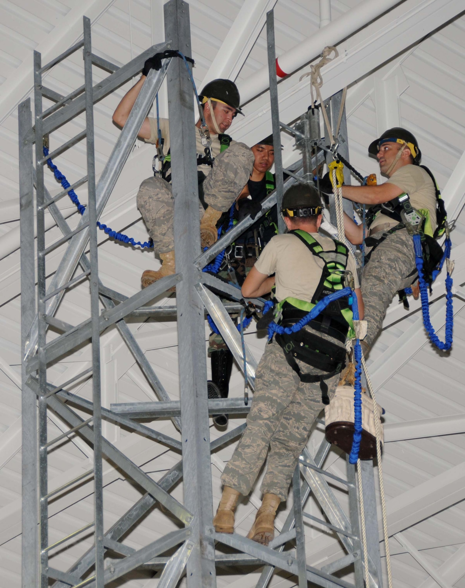 From left, Senior Airman Jonathan Pelletier, Airman 1st Class Rathanak Ear, Senior Airman Jarrett Bowling and Staff Sgt. Warren Macomber from the 85th EIS work on construction of the 40-foot training tower in the bay area of Matero Hall last week.  (U.S. Air Force photo by Kemberly Groue)