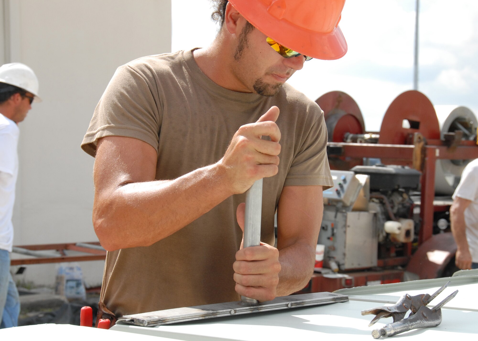 Clay Lambert, R.L. Campbell Construction, bends the corner of the panel into place before cutting it so it connects to other panels as part of the roof of the 919th Logistics Readiness hangar Aug. 3 at Duke Field.  This is just one of many construction projects taking place at Duke Field.    (U.S. Air Force photo/Staff Sgt. Samuel King Jr.)