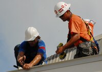 Members of R.L. Campbell Construction fasten panels to the top of the roof of the 919th Logistics Readiness hangar Aug. 3 at Duke Field.  This is just one of many construction projects taking place at Duke Field.    (U.S. Air Force photo/Staff Sgt. Samuel King Jr.)