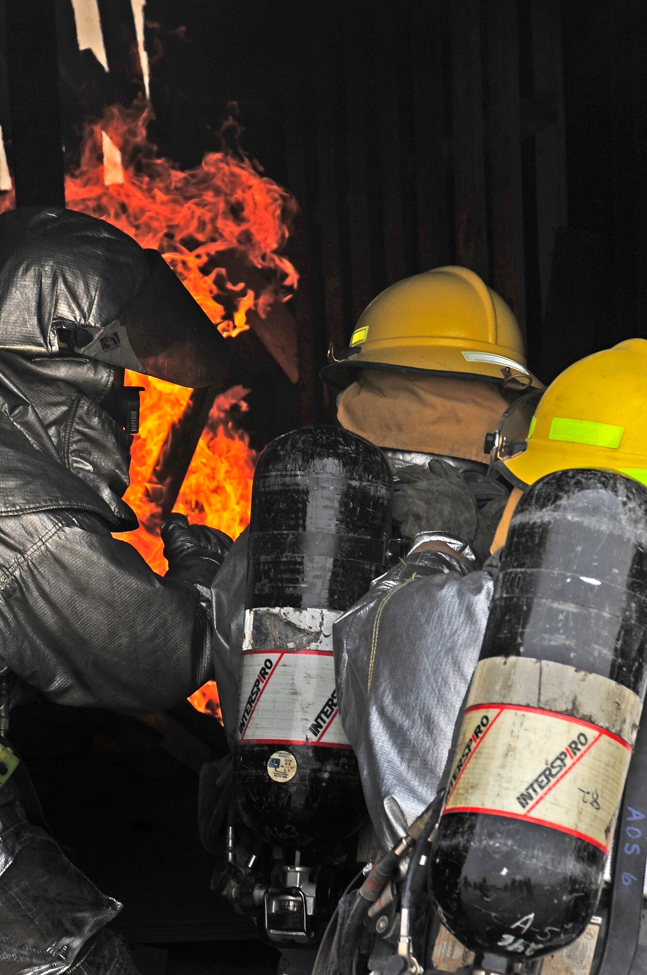 ALI BASE, Iraq - A U.S. Air Force Airmen from the 407th Expeditionary Civil Engineer Squadron directs two Iraqi firefighters as they prepare to enter a burning Container Express (CONEX) here August 3.  Iraqi firefighters from the Dhi Qar province, An Nasiriyah, Iraq.  Airmen from the 407th ECES have been mentoring the Iraqi firefighters for six weeks in order to provide them with adequate fire response experience and training. (U.S. Air Force photo Airman 1st Class Tony R. Ritter)