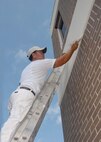 Marvin Miranda, Washington Painting, touches up the bottom of the trim of the 919th Special Operations Group building Aug. 3 at Duke Field.  The painting crew is moving around repainting many of the base buildings.  (U.S. Air Force photo/Staff Sgt. Samuel King Jr.)