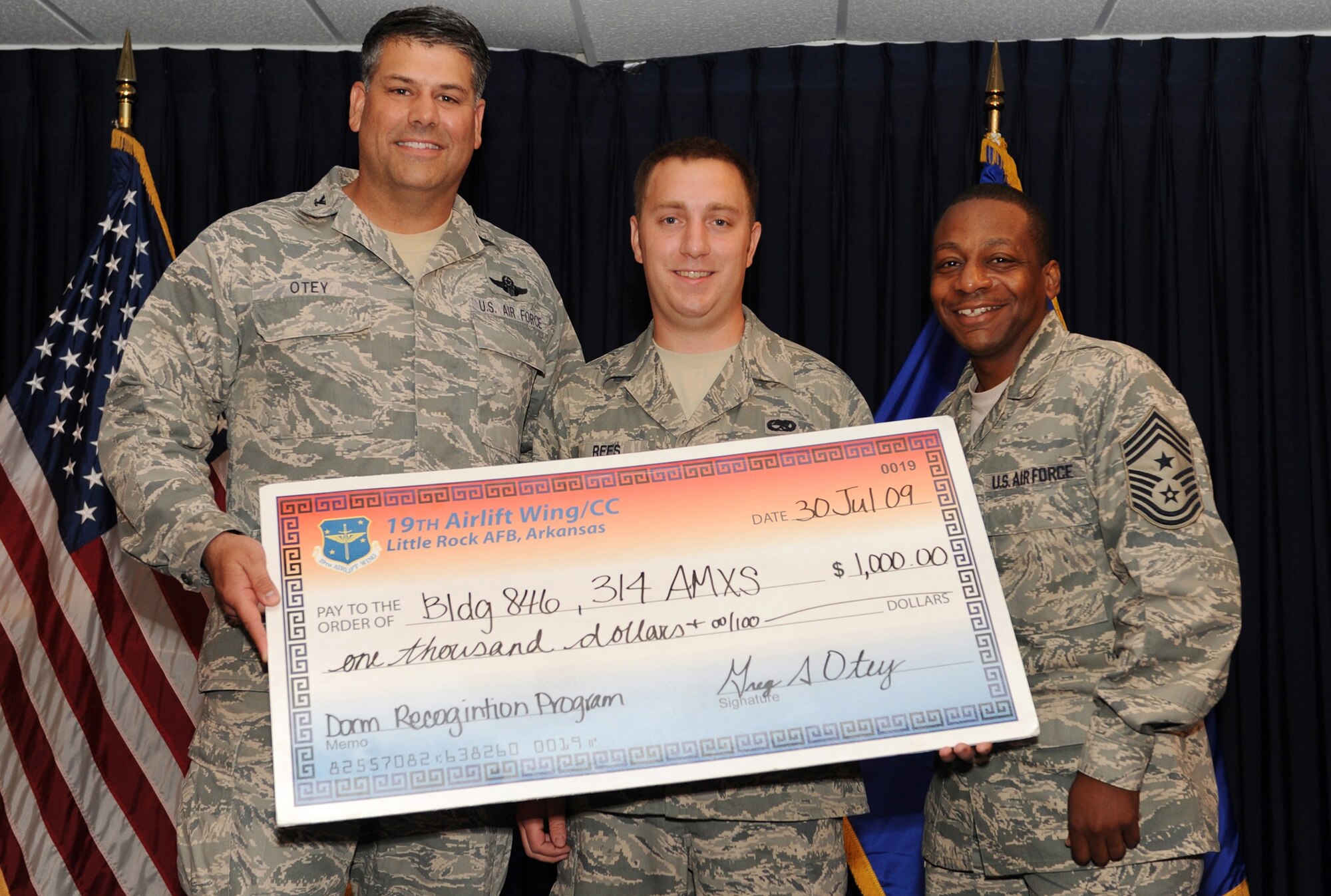 Col. Greg Otey, 19th Airlift Wing commander, and Chief Master Sgt. Anthony Brinkley, 19th Airlift Wing command chief, presents Senior Airman Joshua Rees, 314th Maintenance Squadron, a check for have an outstanding dorm  building at Little Rock Air Force Base, Ark. July 30. The money will go towards the entire dorm building. (U. S. Air Force photo by Senior Airman Jim Araos)