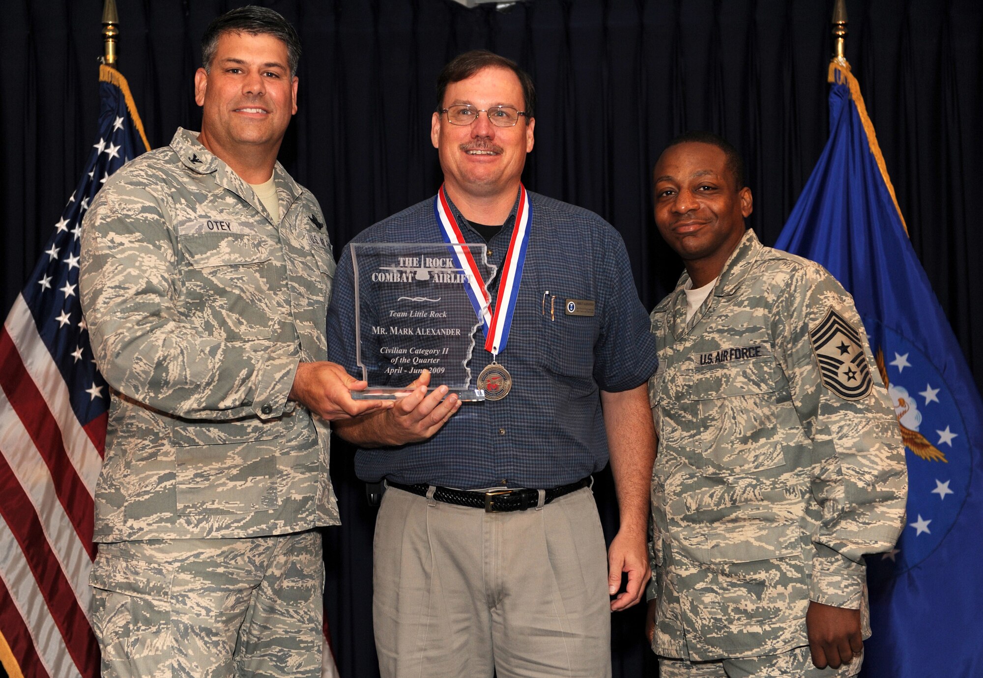 Col. Greg Otey, 19th Airlift Wing commander, and Chief Master Sgt. Anthony Brinkley, 19th Airlift Wing command chief, presents  Mark Alexander, 314th Maintenance Group, a quarterly award for civilian category 2 at Little Rock Air Force Base, Ark. July 30. (U. S. Air Force photo by Senior Airman Jim Araos)