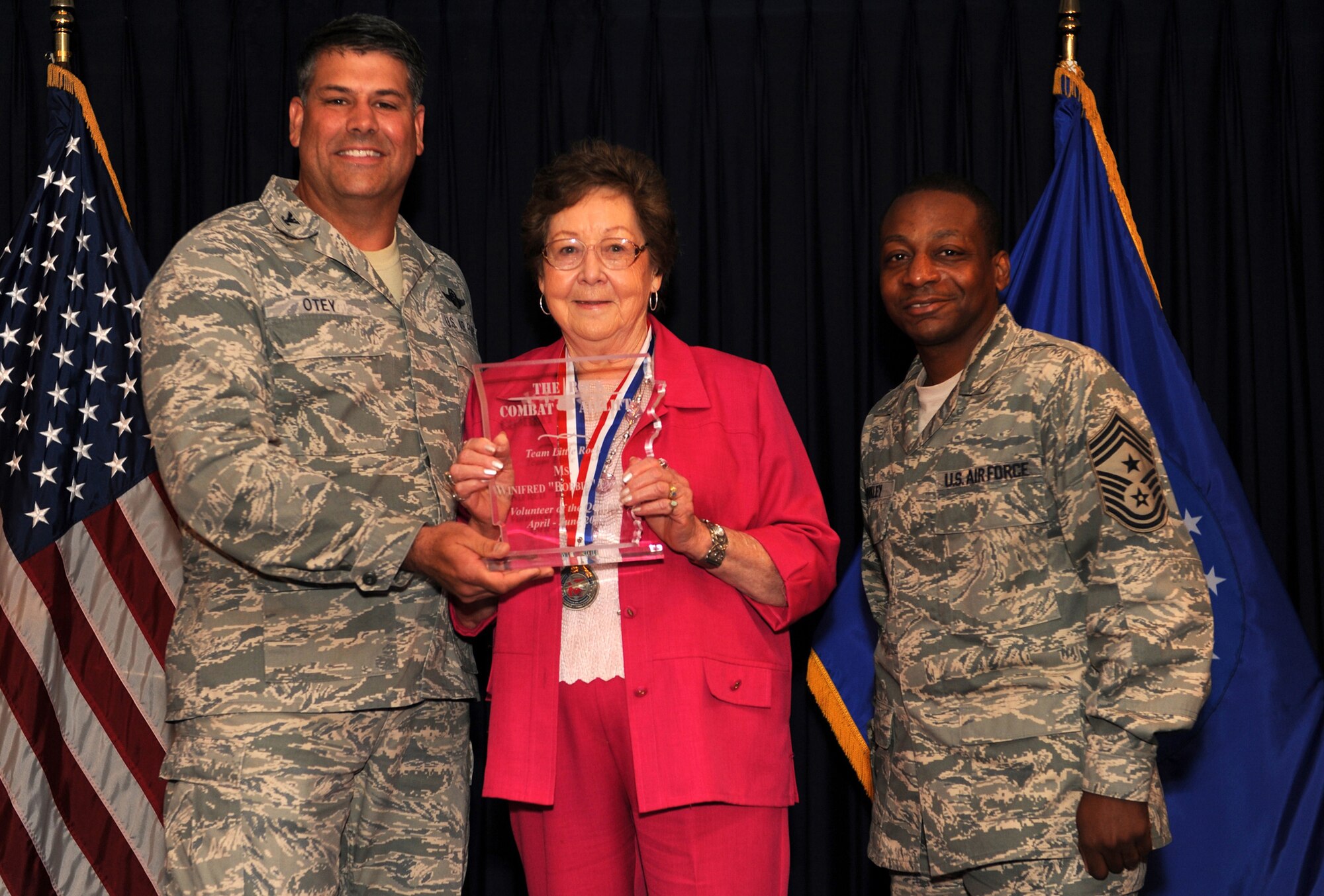 Col. Greg Otey, 19th Airlift Wing commander, and Chief Master Sgt. Anthony Brinkley, 19th Airlift Wing command chief, presents  Winifred Evans, 19th Medical Support Squadron, a quarterly award for volunteer of the quarter at Little Rock Air Force Base, Ark. July 30. (U. S. Air Force photo by Senior Airman Jim Araos)