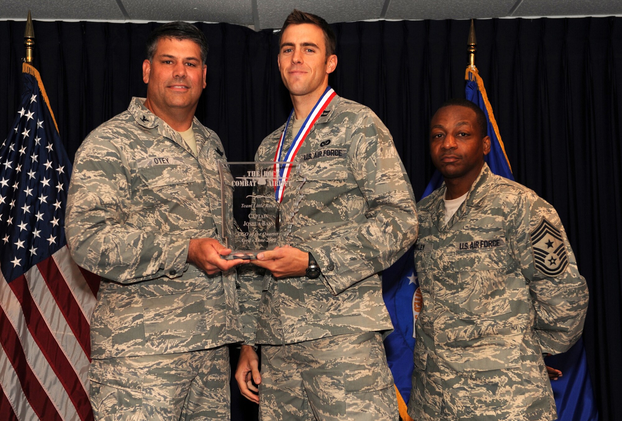 Col. Greg Otey, 19th Airlift Wing commander, and Chief Master Sgt. Anthony Brinkley, 19th Airlift Wing command chief, presents  Capt. Joshua Bass, 19th Civil Engineer Squadron, a quarterly award for company grade officer of the quarter at Little Rock Air Force Base, Ark. July 30. (U. S. Air Force photo by Senior Airman Jim Araos)