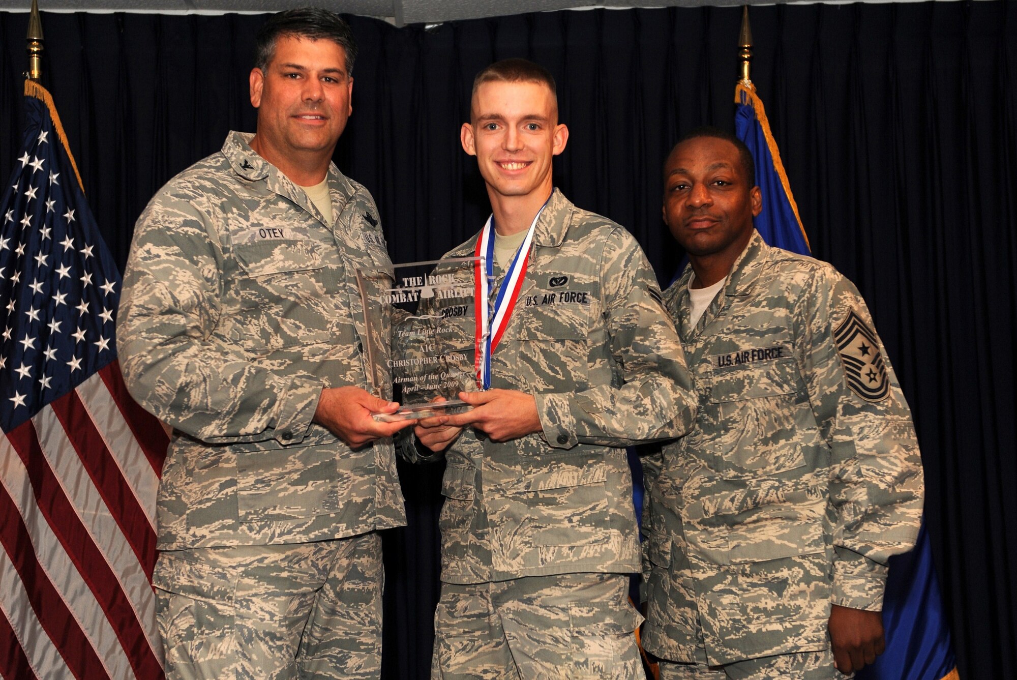 Col. Greg Otey, 19th Airlift Wing commander, and Chief Master Sgt. Anthony Brinkley, 19th Airlift Wing command chief, presents  Airman 1st Class Christopher Crosby, 19th Civil Engineer Squadron, a quarterly award for Airman of the quarter at Little Rock Air Force Base, Ark. July 30. (U. S. Air Force photo by Senior Airman Jim Araos)