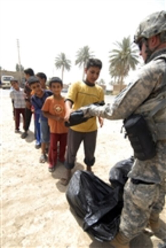 A U.S. Army soldier with the 1st Platoon, 1st Combined Arms Battalion, 63rd Armored Regiment, 2nd Infantry Heavy Brigade Combat Team, 1st Infantry Division hands out backpacks filled with school supplies to Iraqi children in Zaidon market, outside Baghdad, Iraq, on July 23, 2009.  