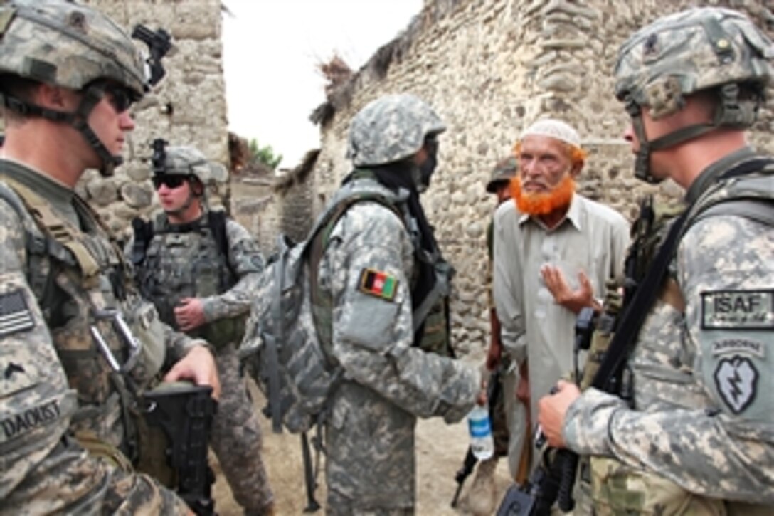 U.S. Army Cpl. James Daoust, left, and Staff Sgt. McCarther use an interpreter to talk with an Afghan man during an air assault mission, Operation Champion Sword, to search Khost province, Afghanistan, July 28, 2009. 