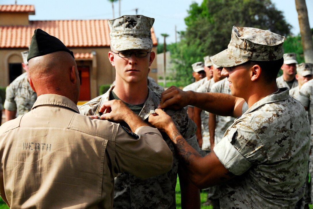 Station commanding officer, Col. Mark Werth, along with Headquarters and Headquarters and Headquarters Squadron martial arts instructor, Sgt. Nicholas Gillmore, pin new rank on Sgt. Samuel Powers Aug. 4, 2009, at the Marine Corps Air Station in Yuma, Ariz. Powers, who left to Japan the very next day, won a Marine Corps Installations West meritorious sergeant board in June.