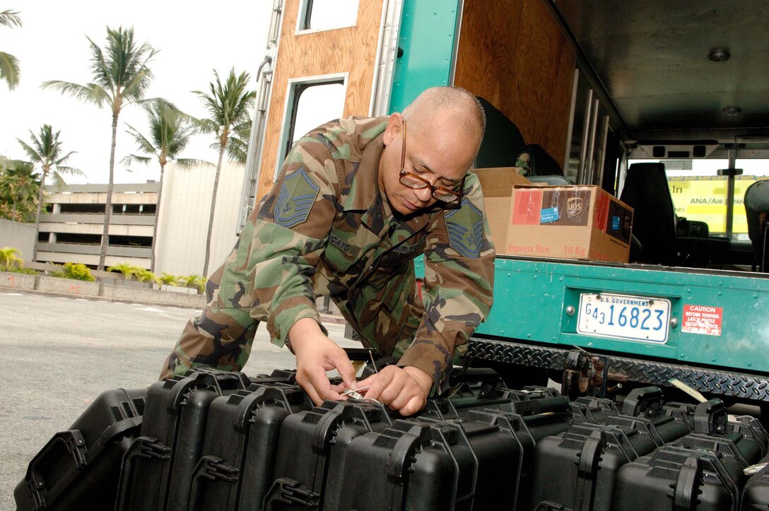 Master Sgt. Robert Tancayo, 624th Civil Engineer Squadron, inspects weapon cases prior to distributing them to deploying members at Honolulu International Airport Friday July 31.  Fifty-four Reservists from the 624th Civil Engineer Squadron, which falls under the 624th Regional Support Group, have been mobilized to deploy to Afghanistan for six months. This is a "partial" mobilization, meaning half the squadron is being mobilized as opposed to the entire squadron. Once in the AOR, the CE team will be supporting the Army at Bagram. (U.S. Air Force photo/Mark Bates)
