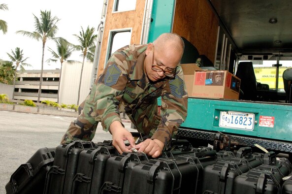 Master Sgt. Robert Tancayo, 624th Civil Engineer Squadron, inspects weapon cases prior to distributing them to deploying members at Honolulu International Airport Friday July 31.  Fifty-four Reservists from the 624th Civil Engineer Squadron, which falls under the 624th Regional Support Group, have been mobilized to deploy to Afghanistan for six months. This is a "partial" mobilization, meaning half the squadron is being mobilized as opposed to the entire squadron. Once in the AOR, the CE team will be supporting the Army at Bagram. (U.S. Air Force photo/Mark Bates)
